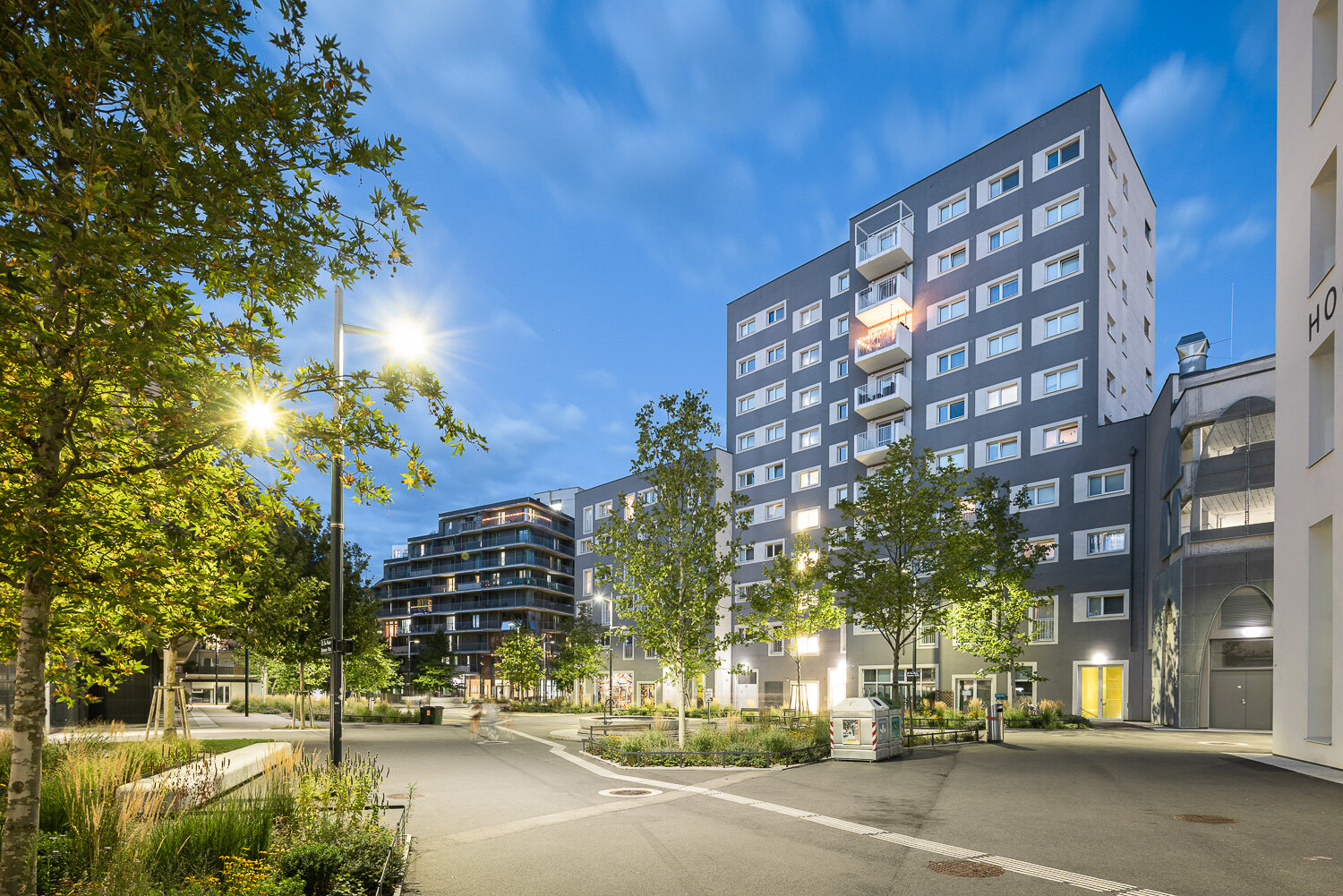 begrünter Platz am Abend mit Straßenlaternenlicht und modernen Gebäuden