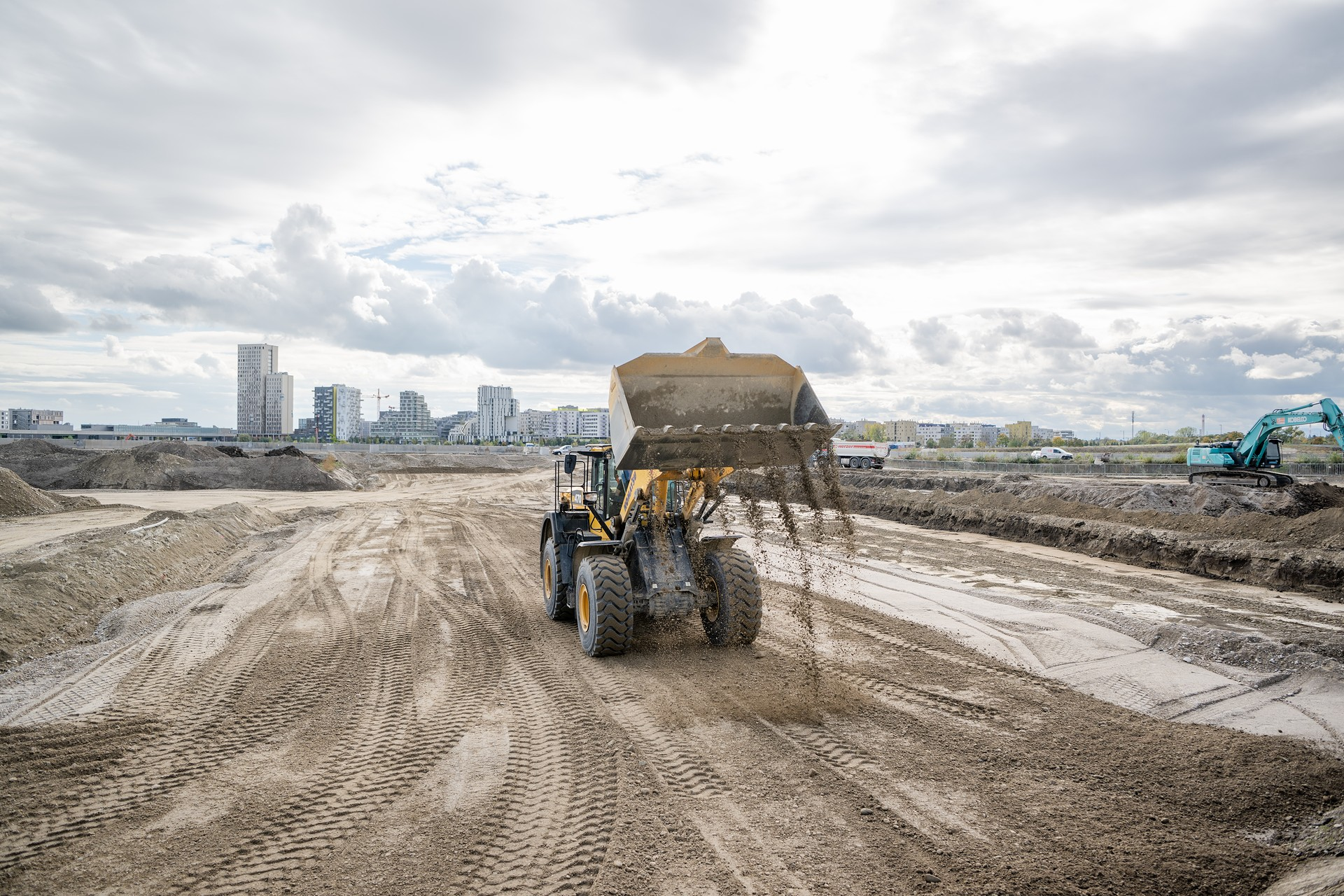 Bagger auf einem Baufeld mit der Skyline von aspern Seestadt