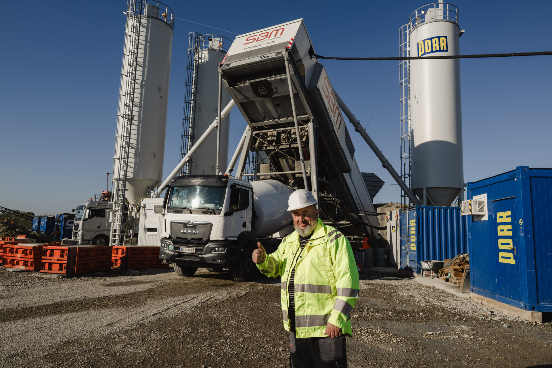 Bauarbeiter vor einem Betonmischwerk und LKW