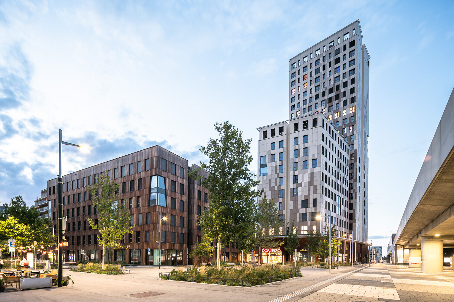 begrünter Platz mit modernen Bürogebäuden mit Holzfasssade