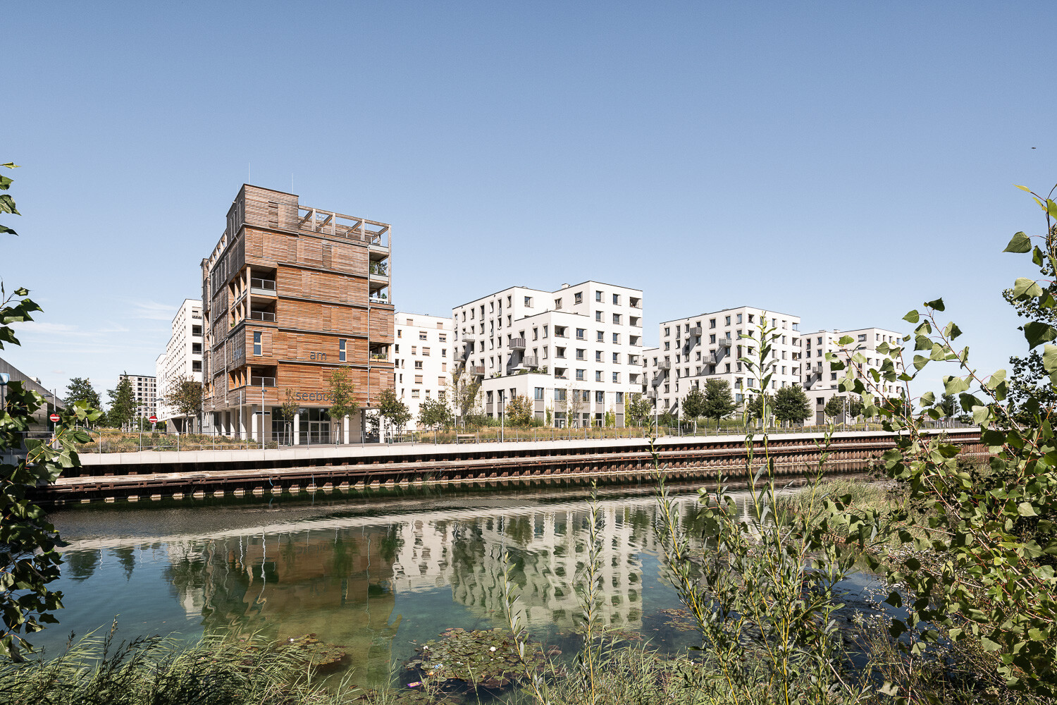 Moderne Gebäude spiegeln sich in einem Wasserarm des Sees. 