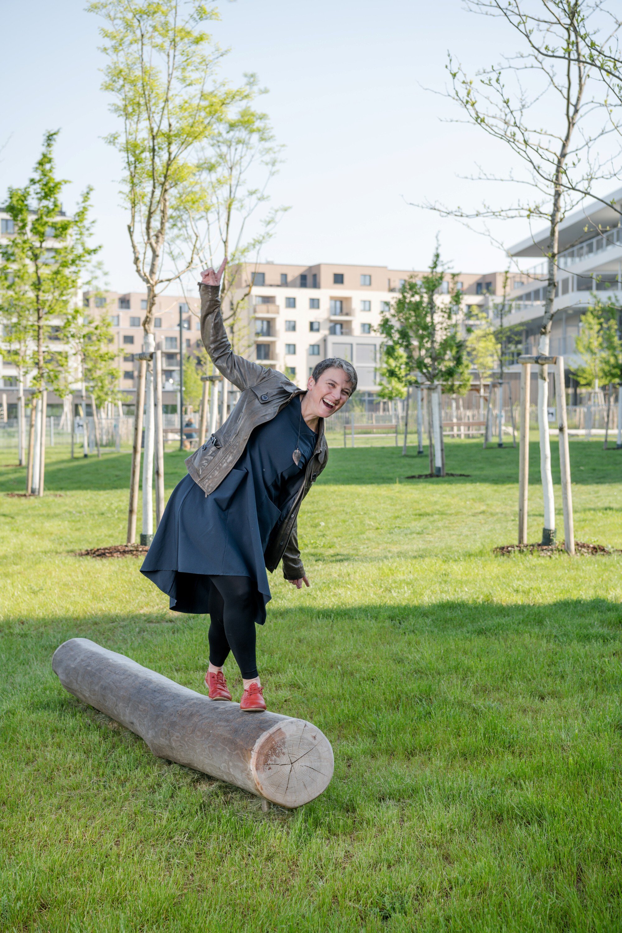 Elisabeth Oberzaucher im Elinor-Ostrom-Parrk Elisabeth Oberzaucher lacht, während sie auf einer großen Wiese in der Seestadt auf einem Baumstamm balanciert