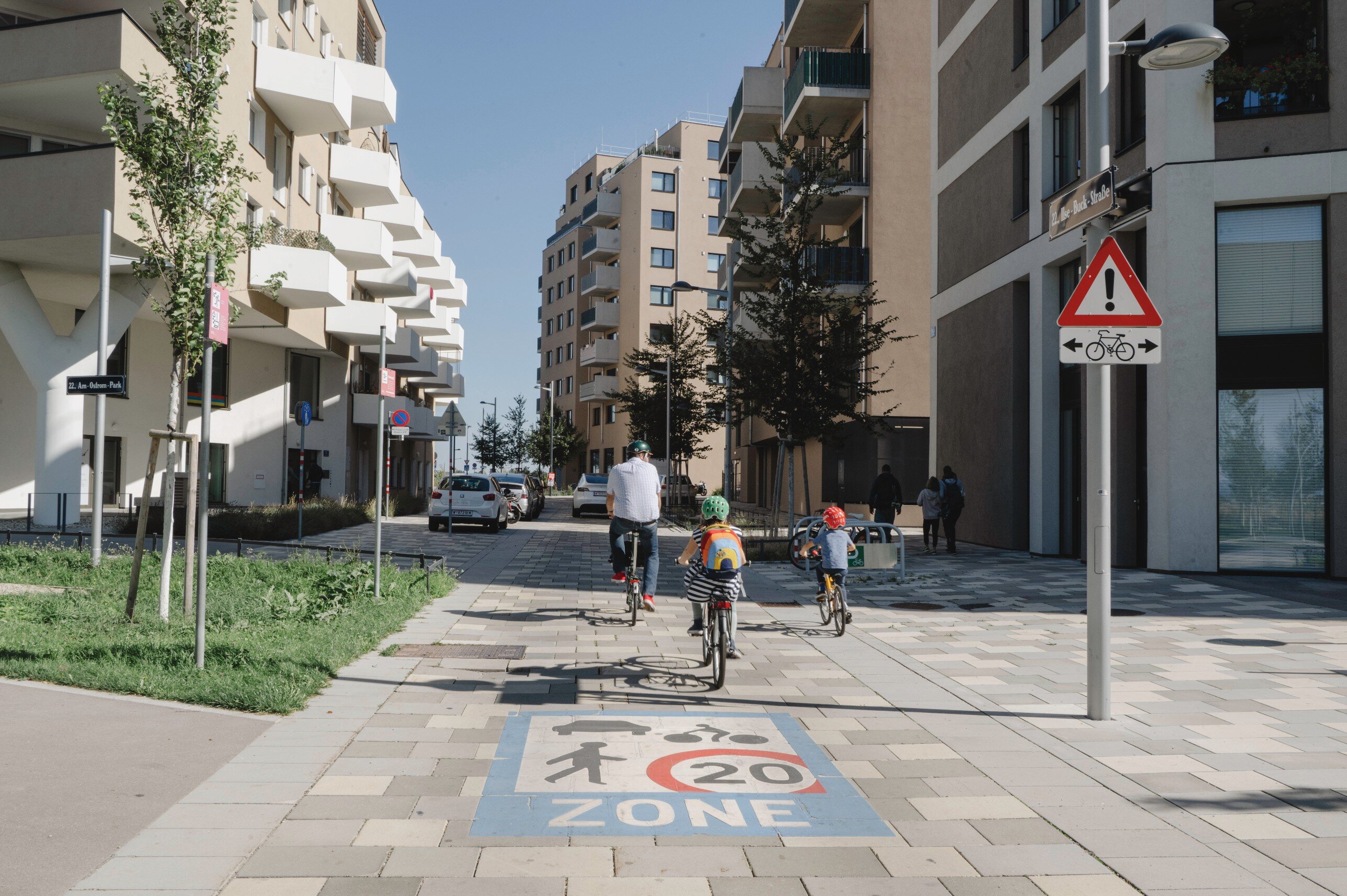 Drei Radfahrer fahren auf einer gepflasterten Straße. 