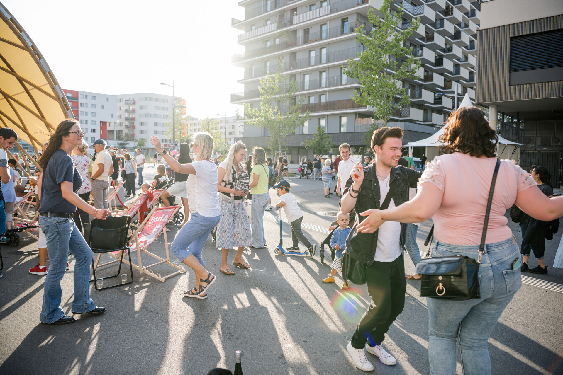 Strassenfest22_Tanz Eine Gruppe Menschen tanzt in gleißendem Sonnenlicht auf der Straße.