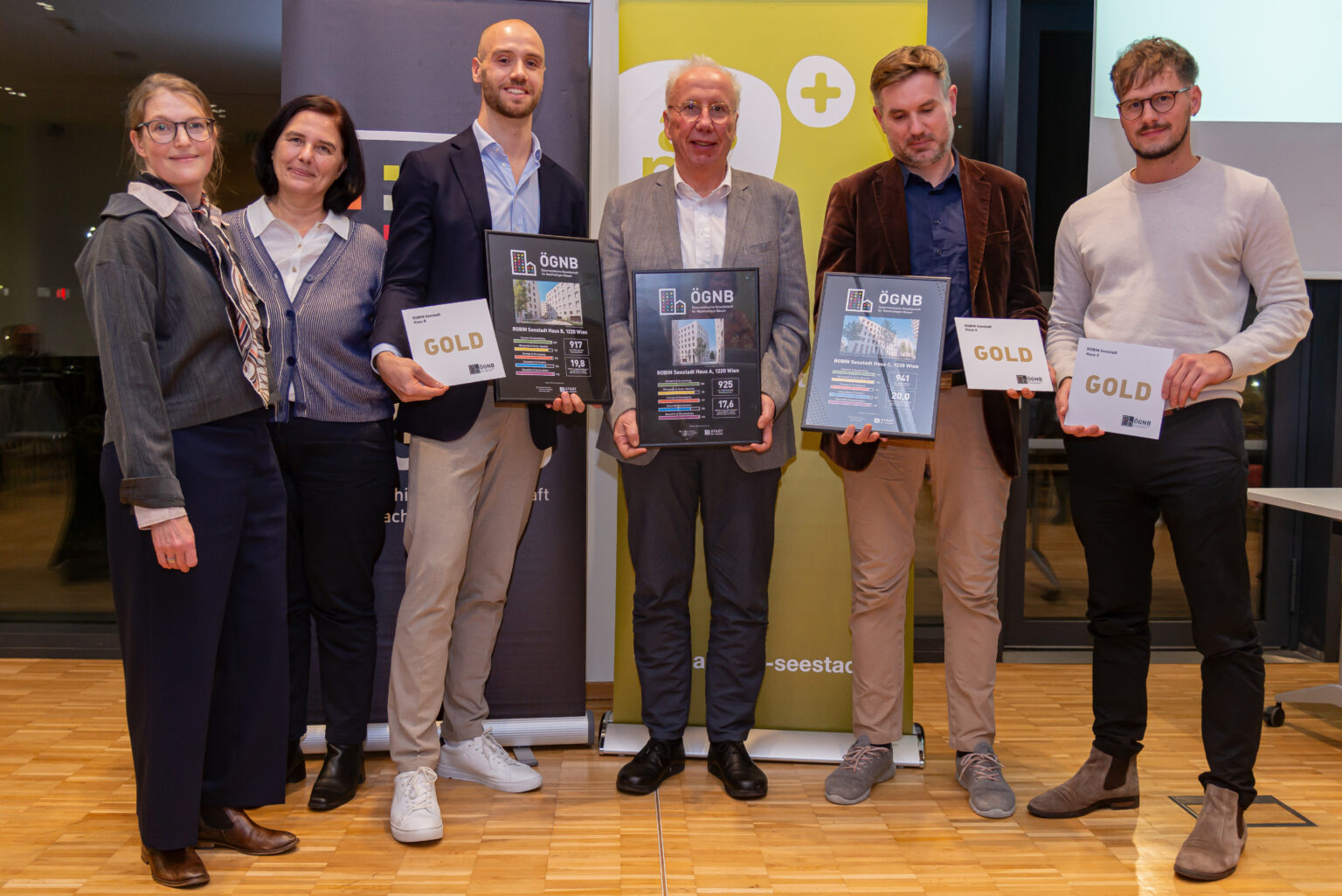 Gruppenbild von Gewinner*innen bei der ÖGNB-Auszeichnungsveranstaltung. Personen halten die Auszeichnung in der Hand. 