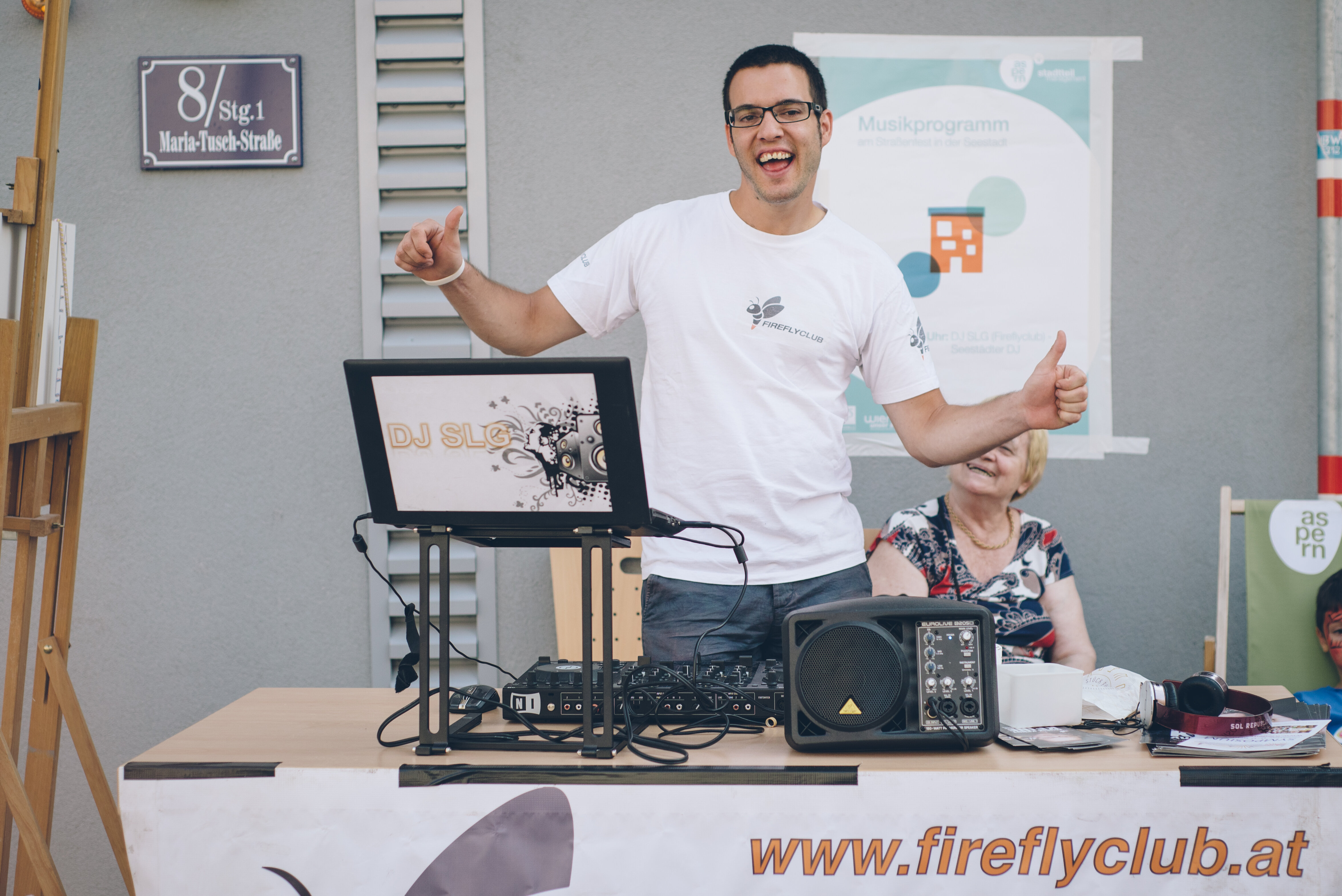 DJ SLG schaut in die Kamera. Im Vordergrund ist sein Musikequipment.