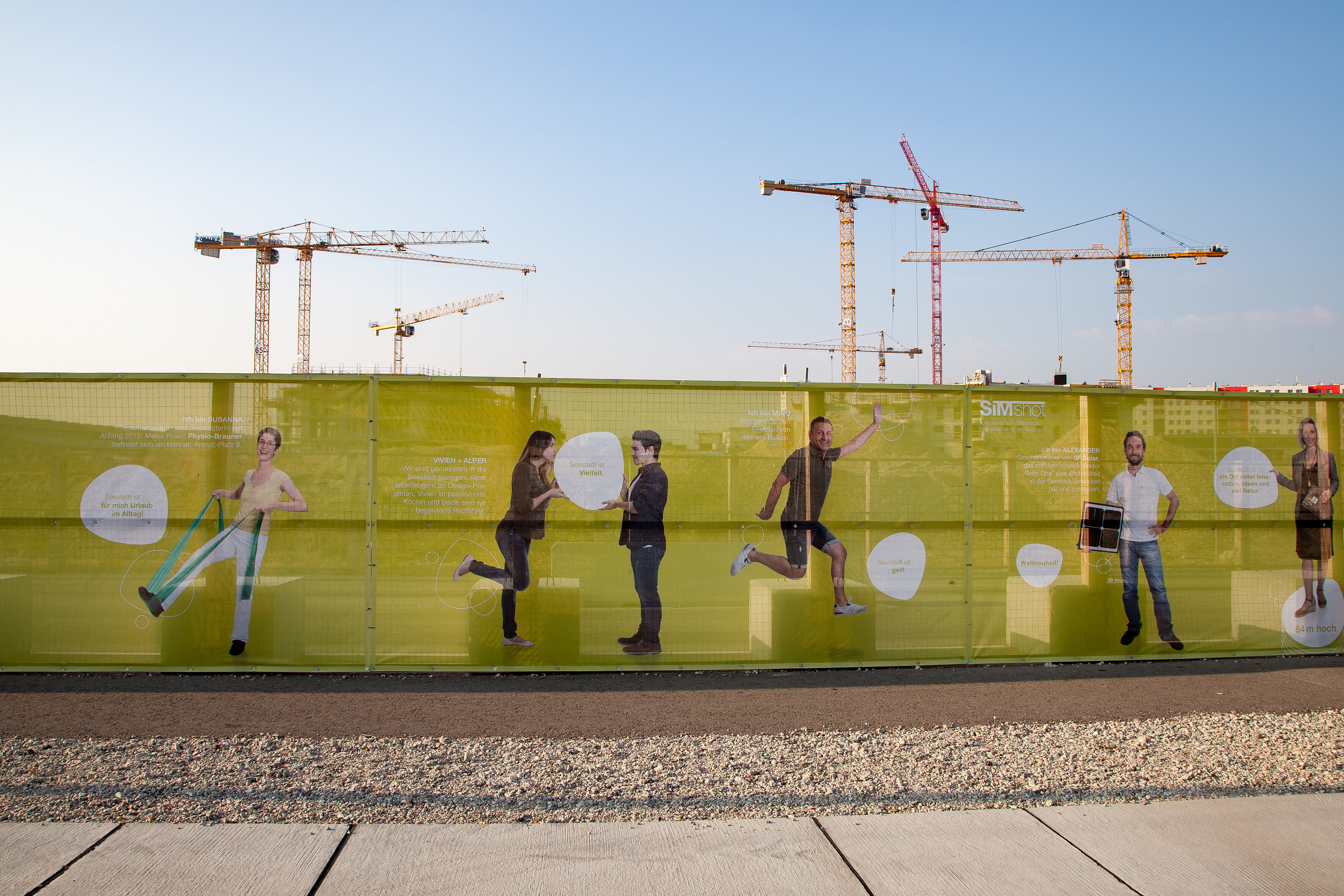 Bauzaun zum Seeparkquartier mit Kränen im Hintergrund