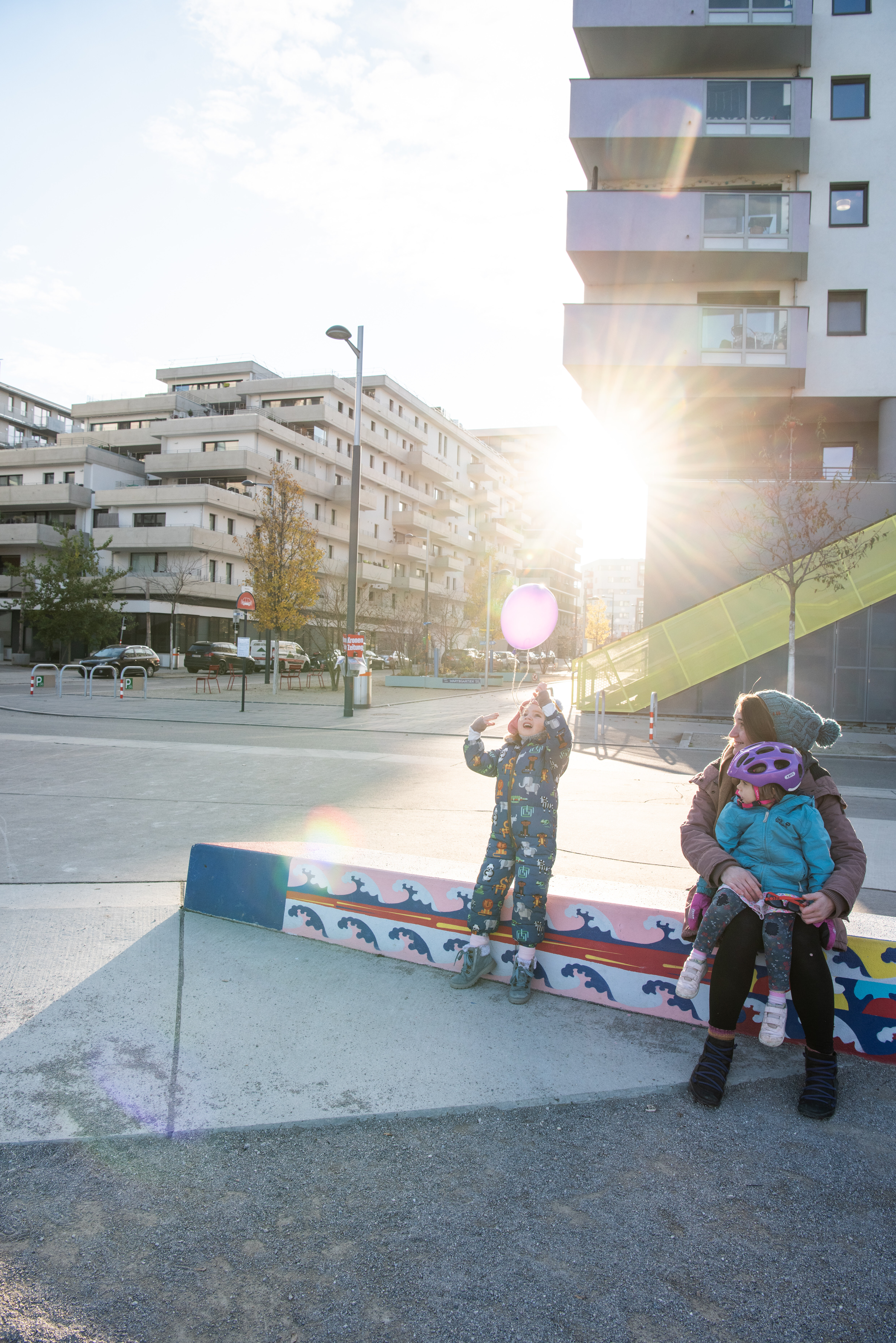Frau mit zwei Kindern, ein Kind hat einen Ballon. Im Gegenlicht fotografiert. 