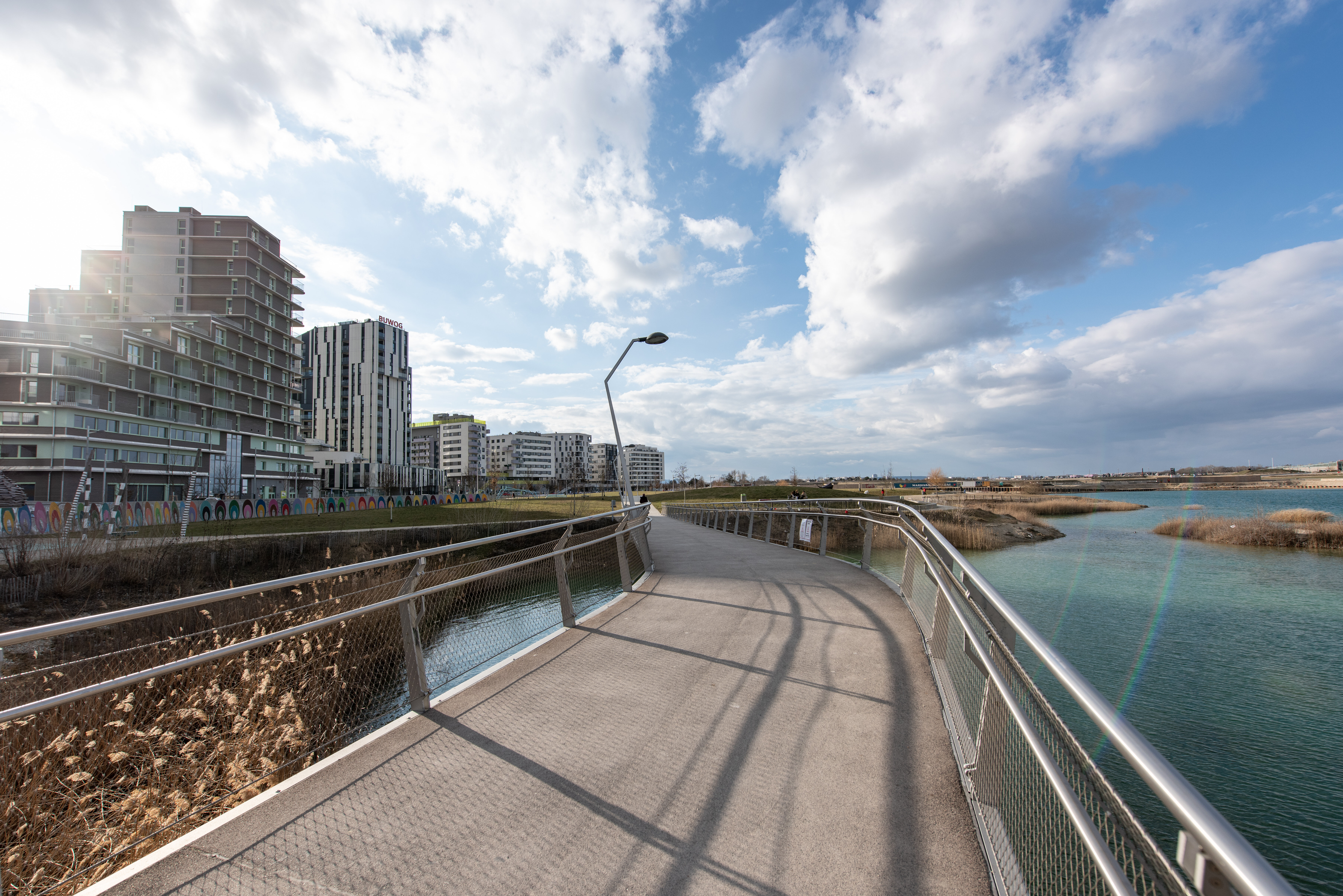 Bild einer Brücke über dem See, im Gegenlicht fotografiert. 