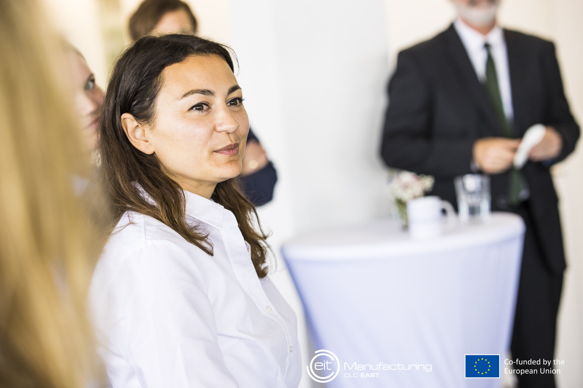 Frau bei der Veranstaltung, dahinter Stehtisch