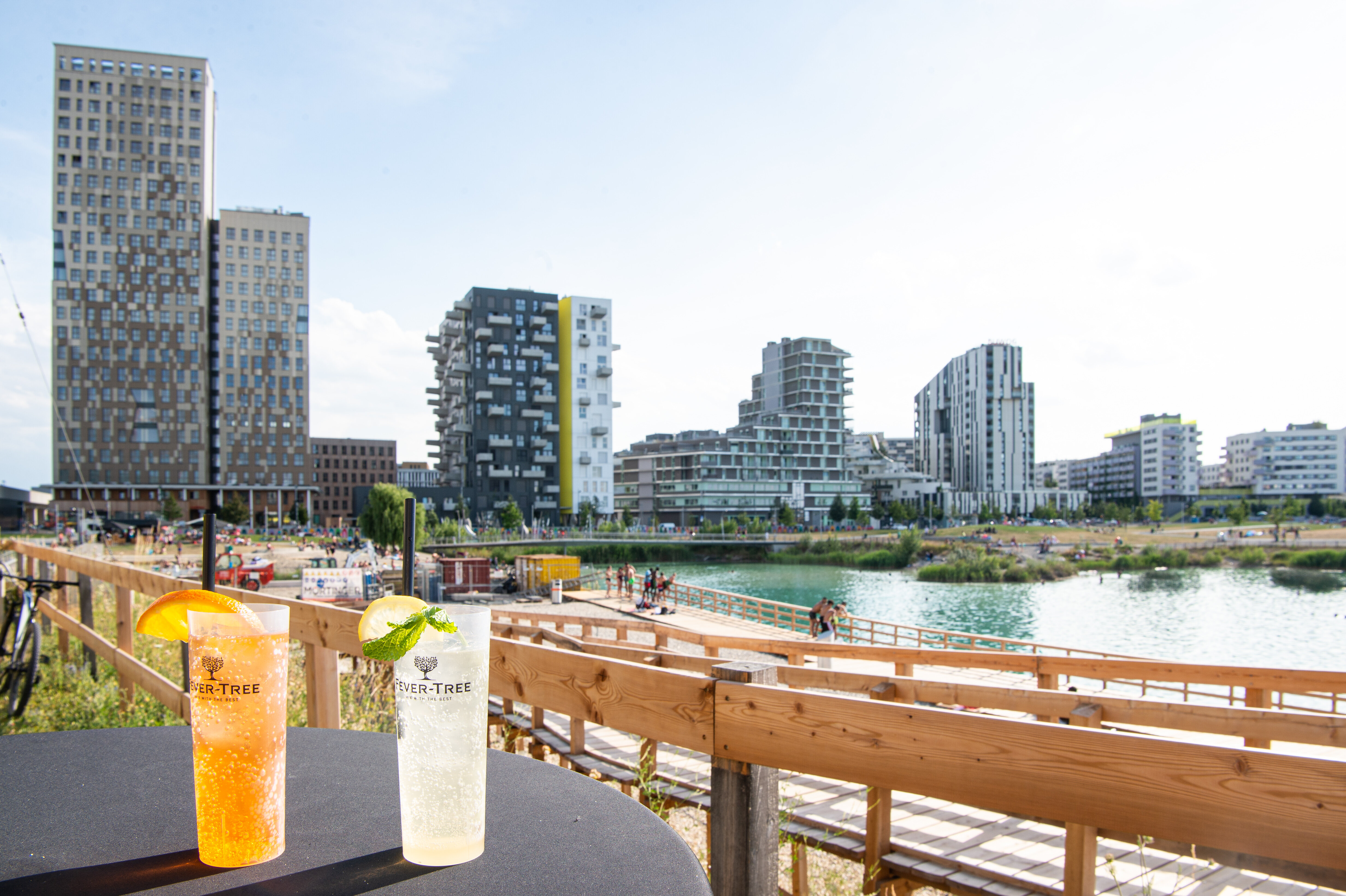 Zwei Sommerdrinks auf einem Tisch im Vordergrund, im Hintergrund die Skyline der Seestadt. 