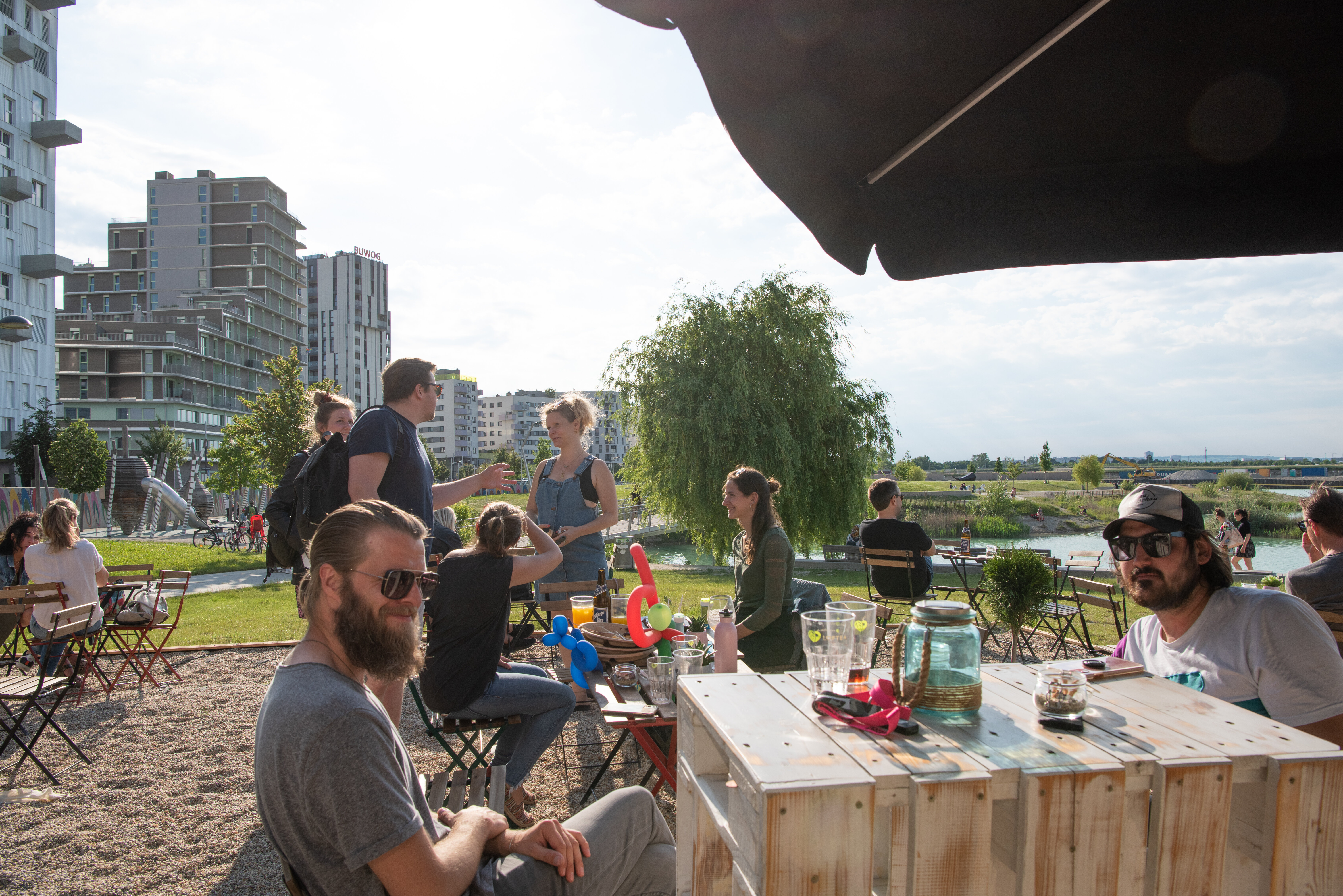 Mehrere Personen mit Getränken in einer Outdoor-Bar. 
