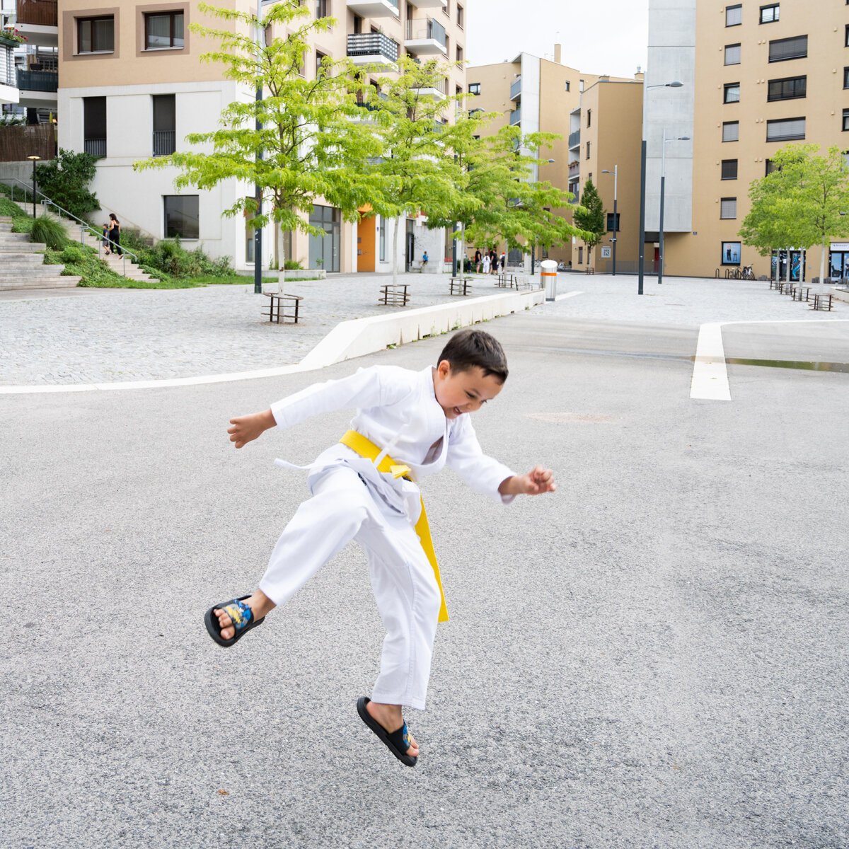 Junge in weißem Kampfanzug und gelben Gürtel springt
