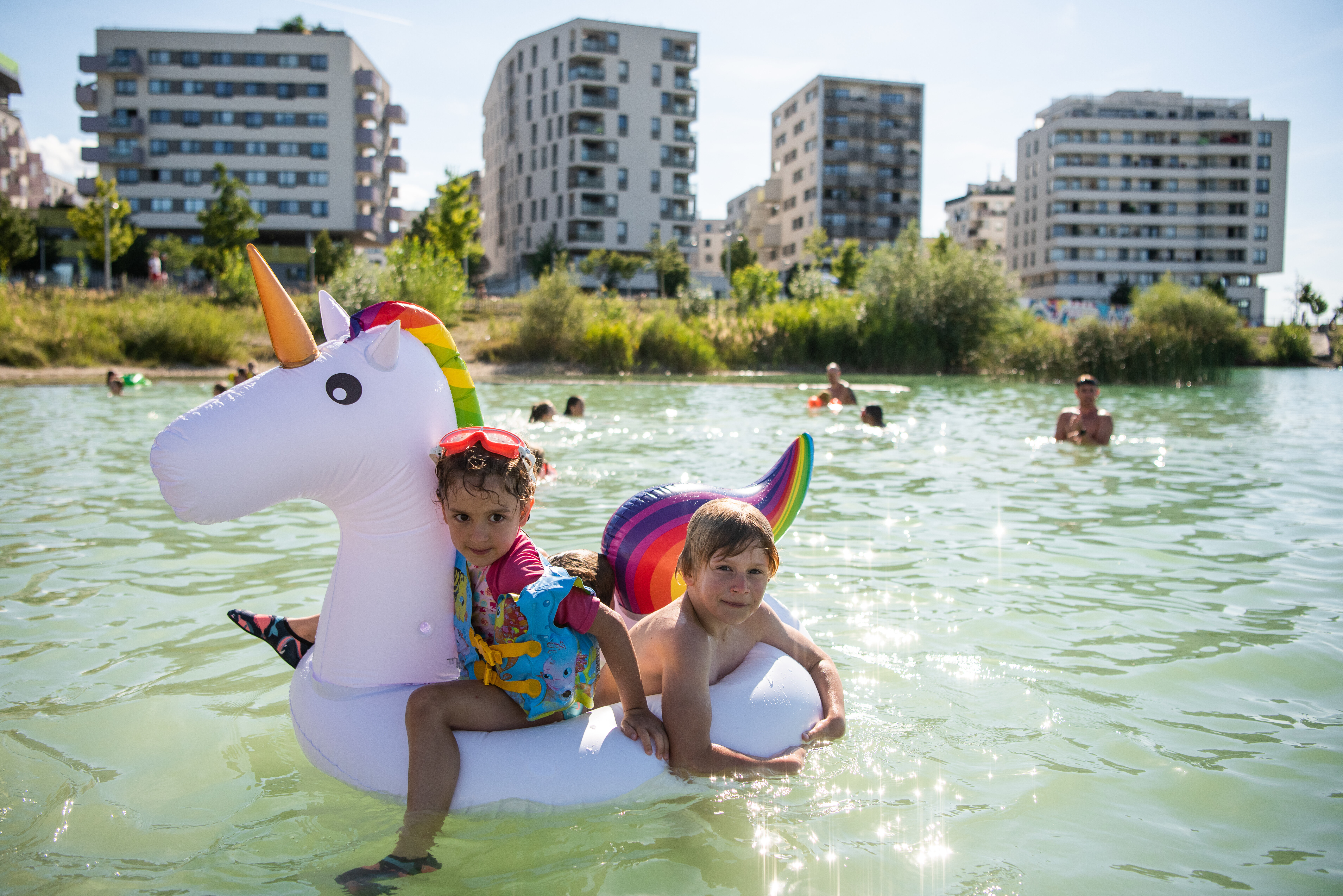 Badetag in der Seestadt mit zwei Kindern auf einem Einhornschwimmreifen