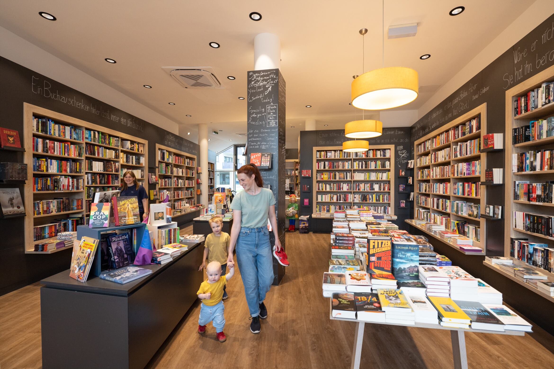 Mutter mit zwei Kindern gehen durch die Buchhandlung Seeseiten