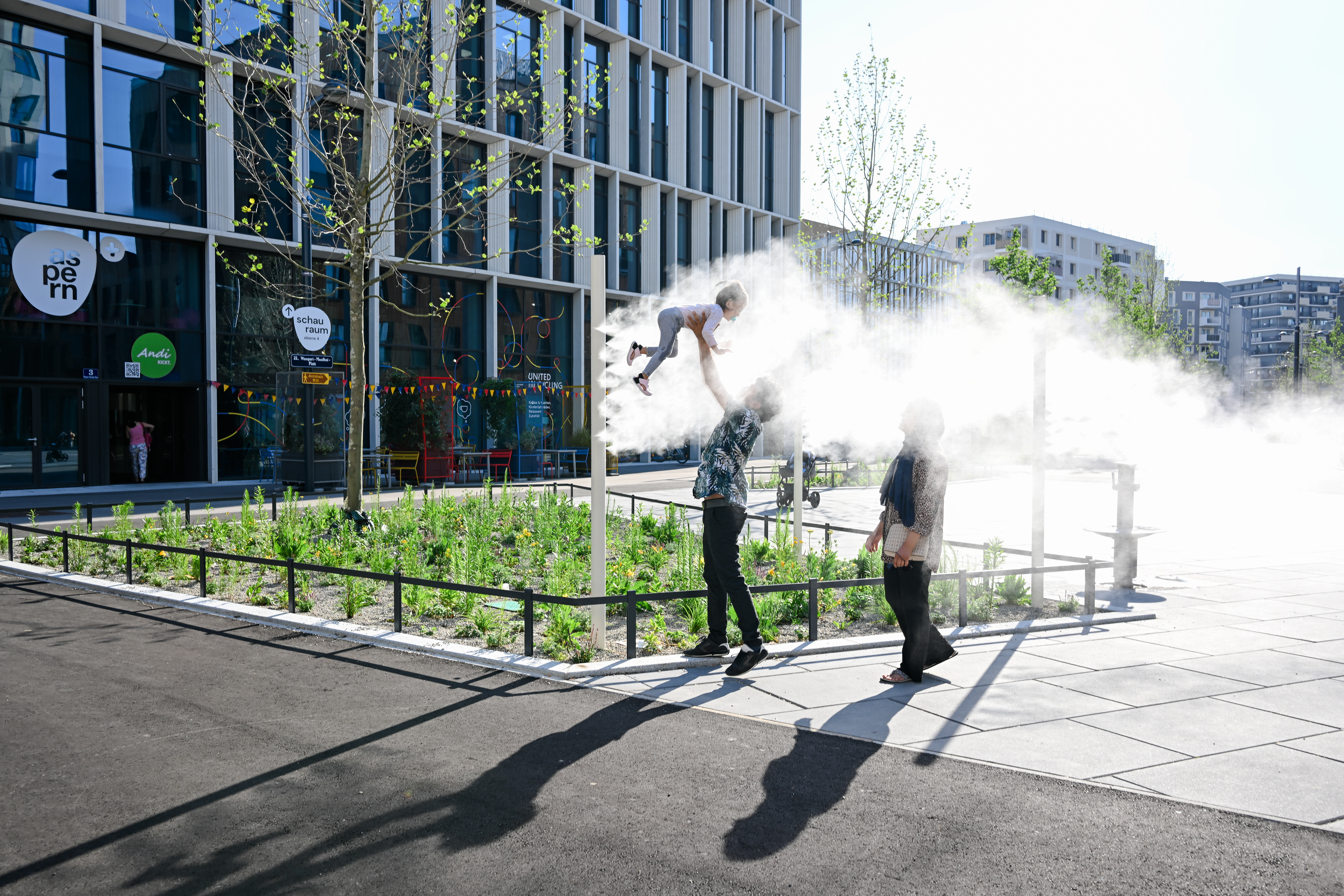 zwei Erwaschsene einer hält das Kind in der Luft im Foto ist eine Nebelwolke