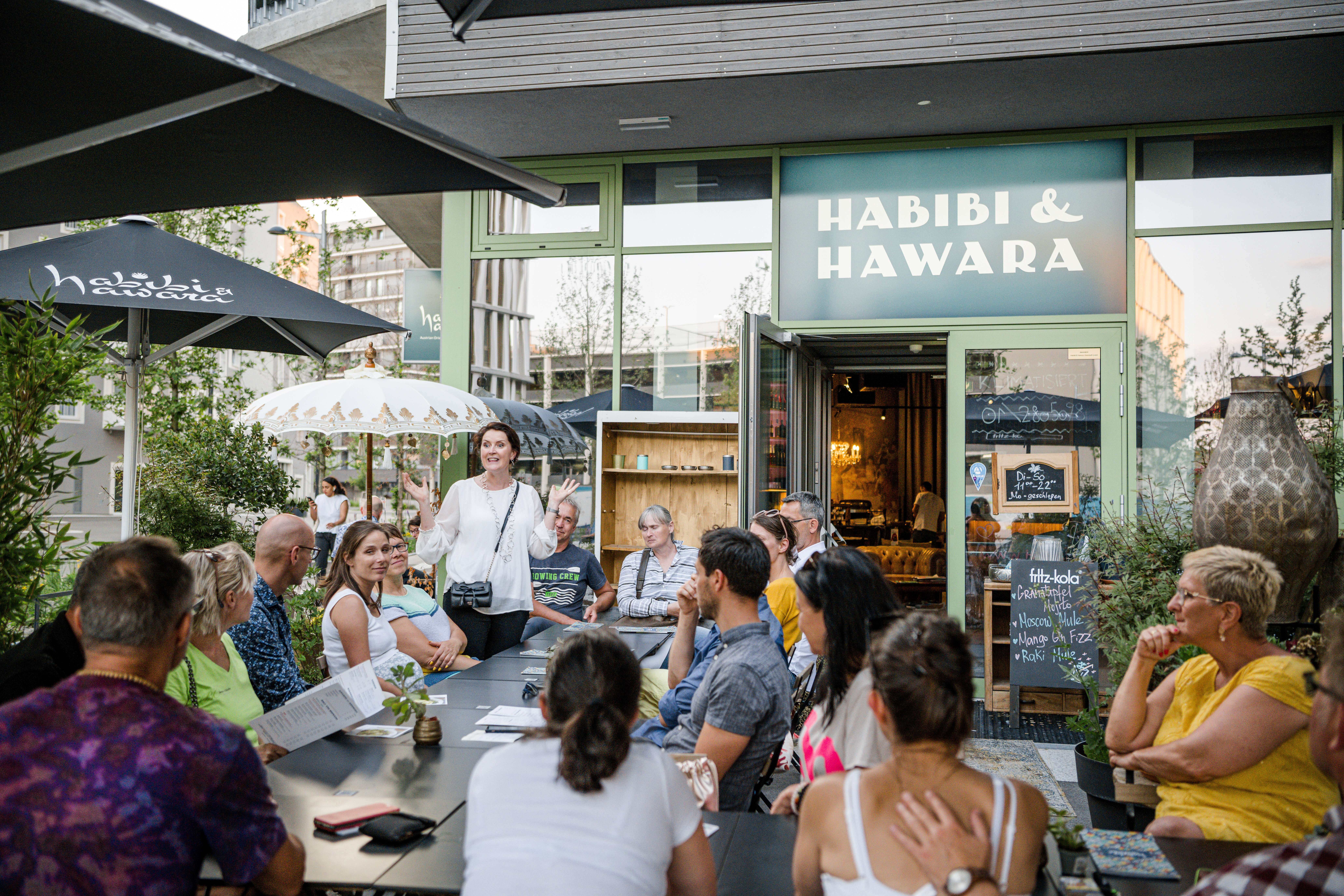 Im Außenbereich von HABIBI und HAWARA sitzen Unternehmer die der Vortragenden Claudia Glawischnig zu hören
