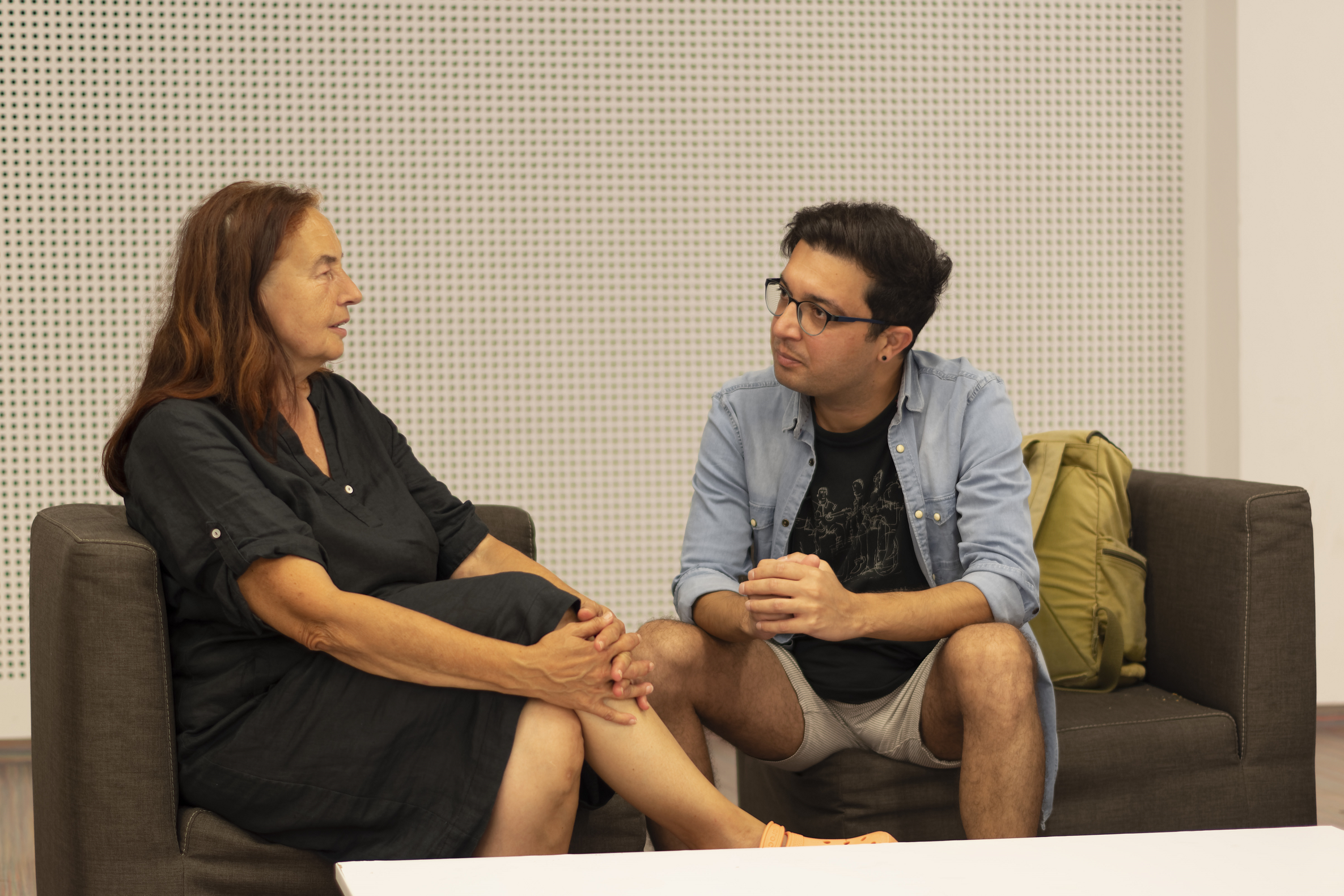 Frau und junger Mann sitzen auf Couch und unterhalten sich