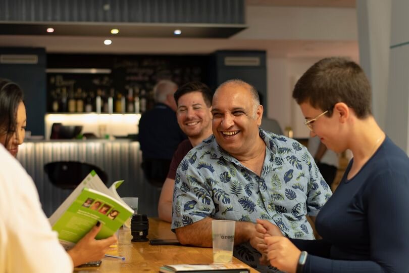 Drei Menschen sitzen an einem Tisch und lachen