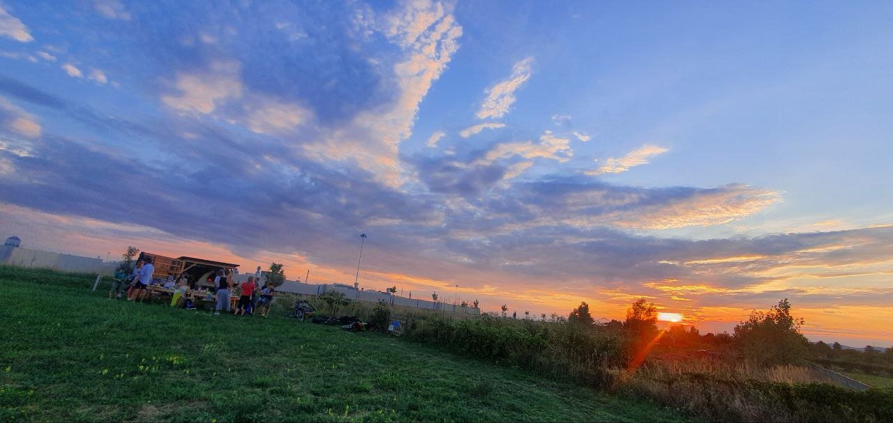 Der Lehmofen mit Menschen, die essen und trinken. Die Sonne geht gerade unter