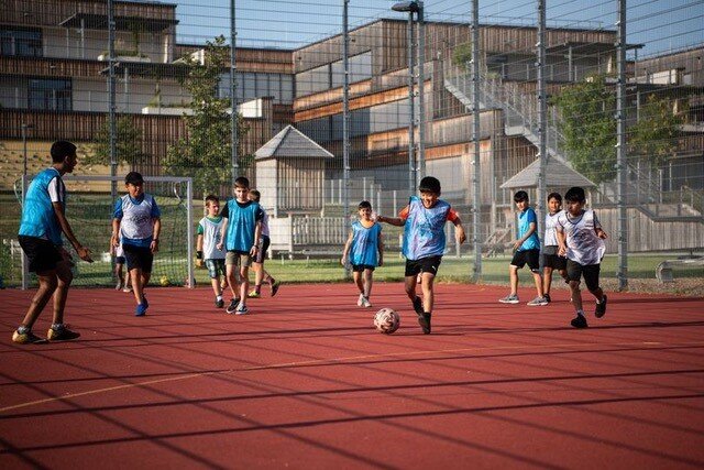 Kinder spielen in einem Sportkäfig Fußball.