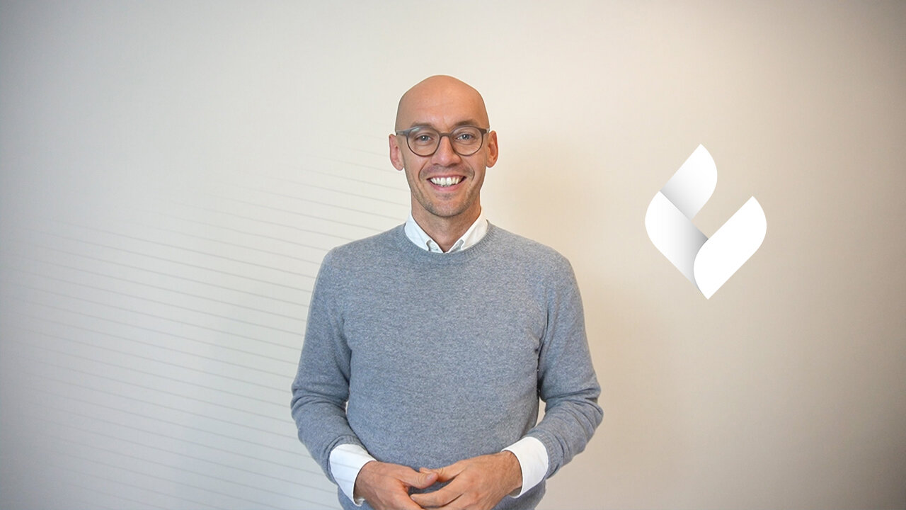 Bartosz Stankiewicz, Geschäftsführer von individual, steht vor dem Logo von individual.