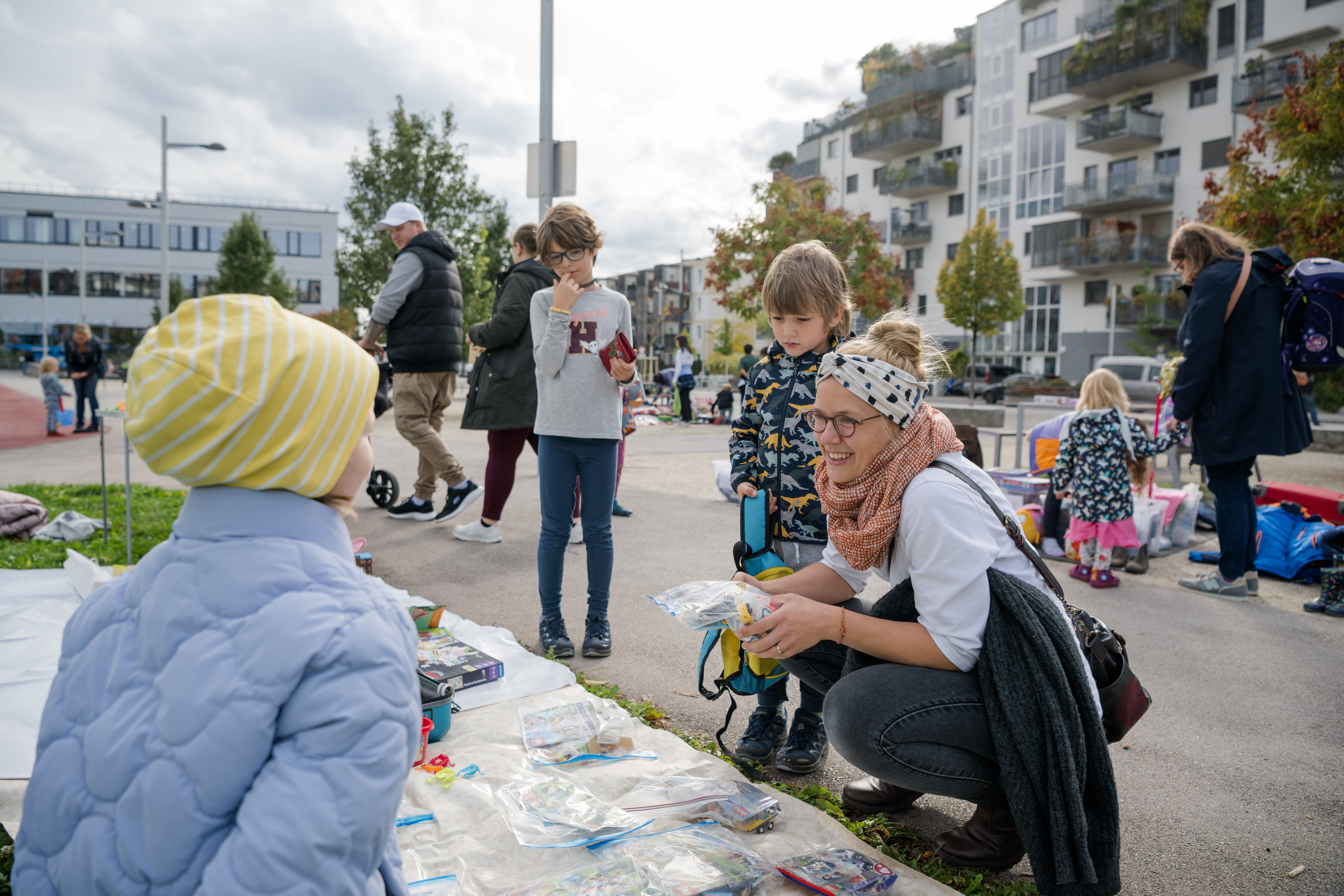 Kinder verkaufen auf Decken ihre Spielsachen und eine Mutter ist begeistert.