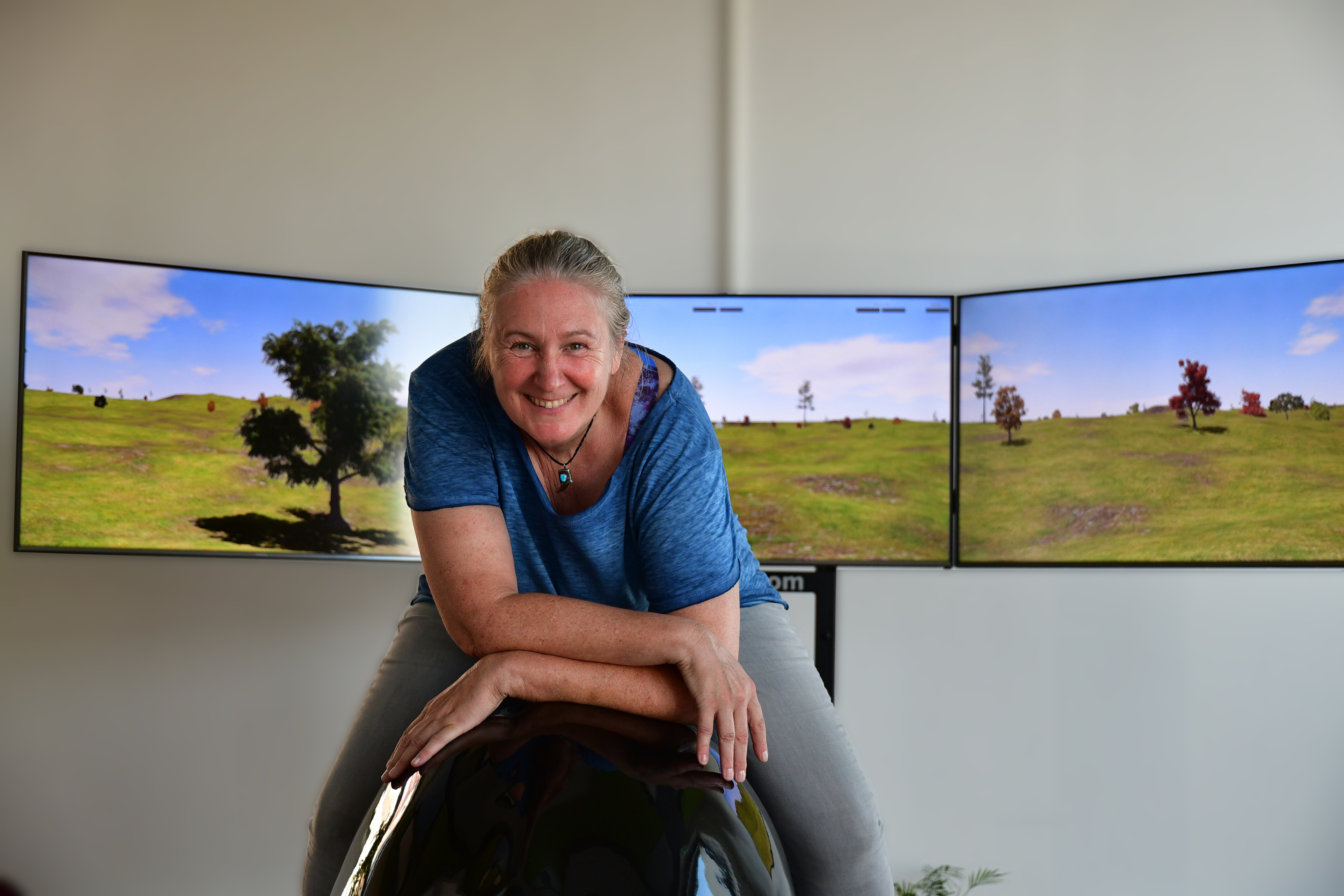 Eine Frau sitzt auf einem Reitsimulator und lacht in die Kamera.