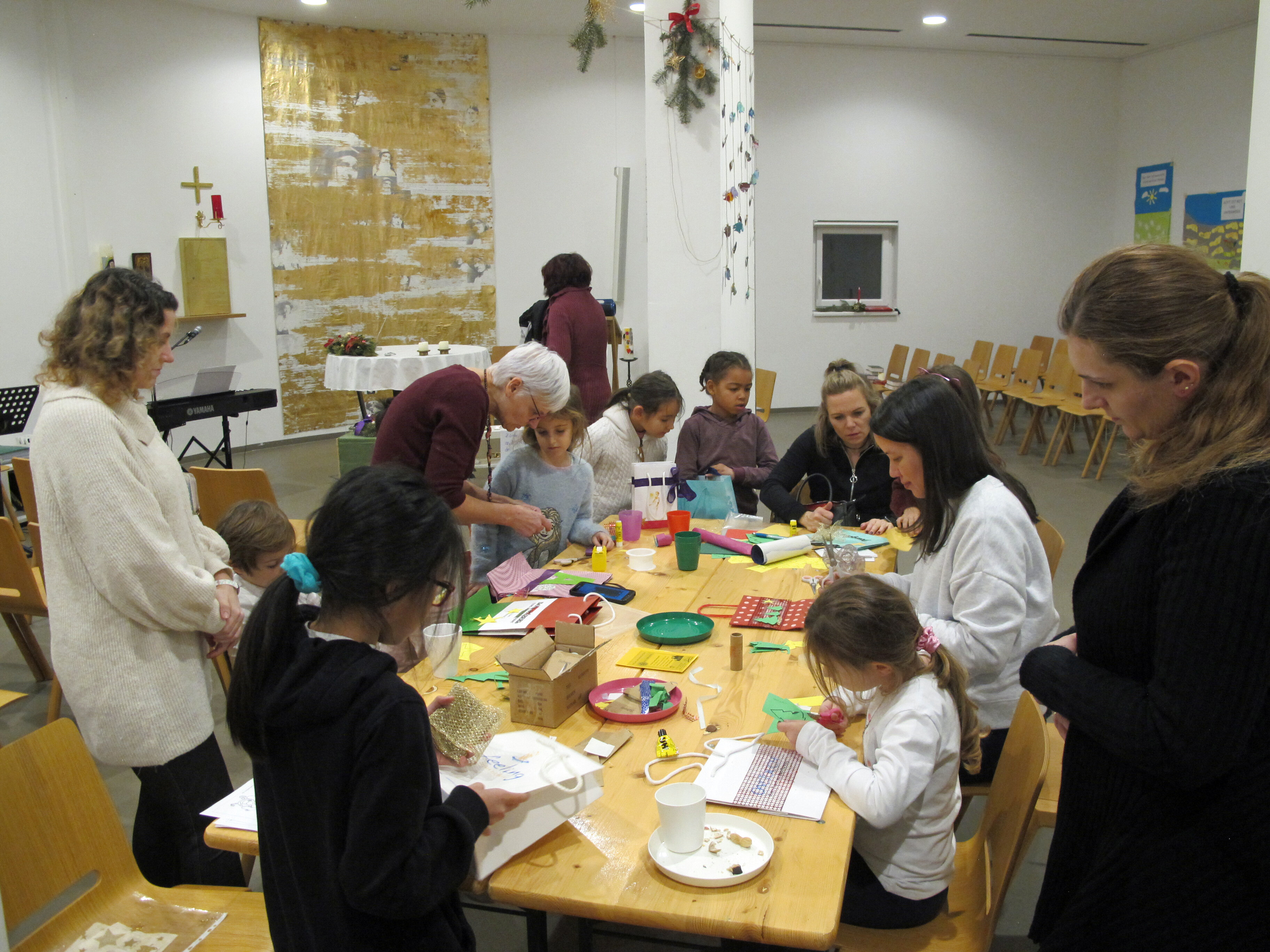 Erwachsene und Kinder sitzen um einen Tisch im Seelsorgezentrum und basteln.