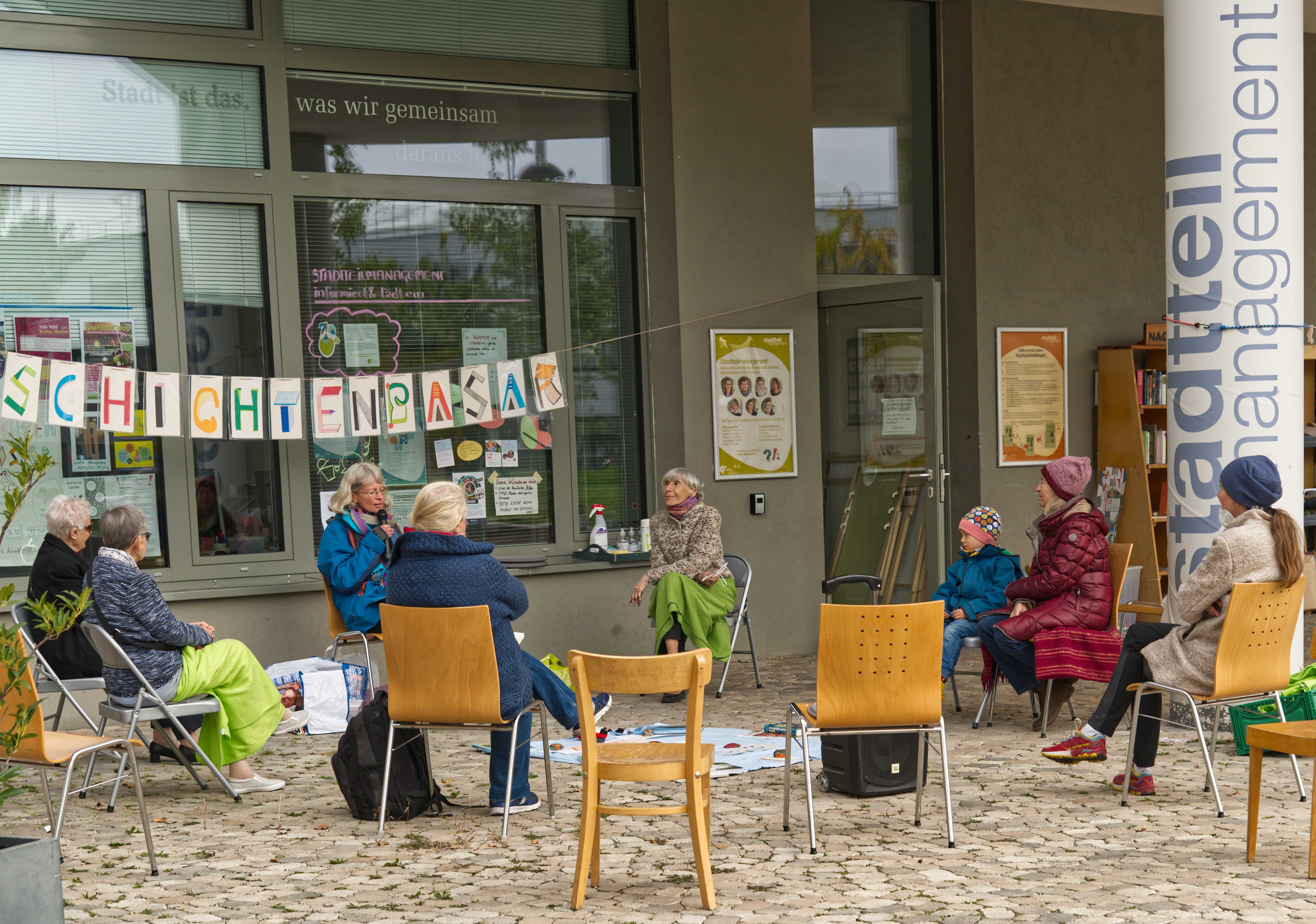 Menschen auf Stühlen vor dem Stadtteilmanagement