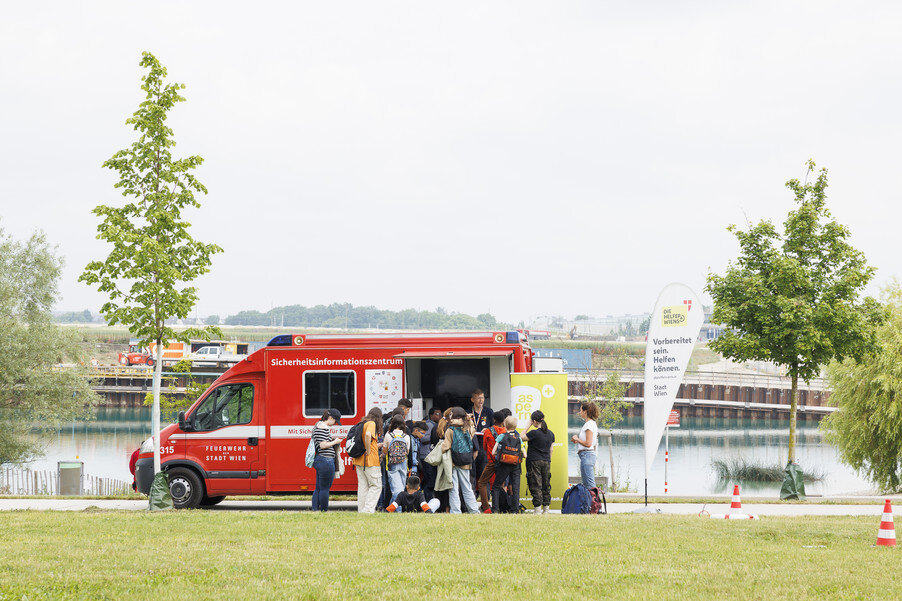 Menschen stehen bei einem Einsatzfahrzeug der Feuerwehr
