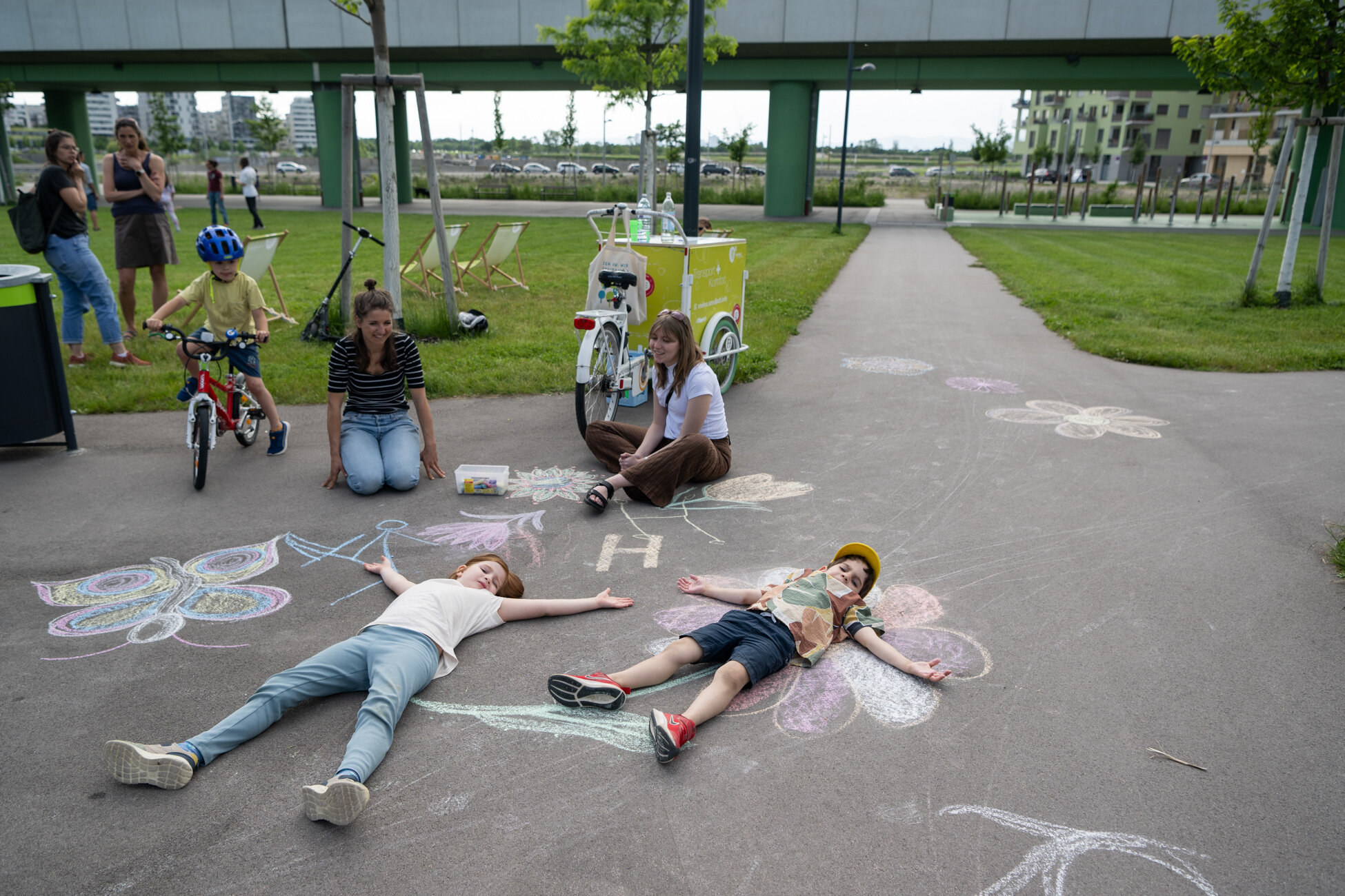 Kinder liegen auf Kreidenzeichnungen am Boden