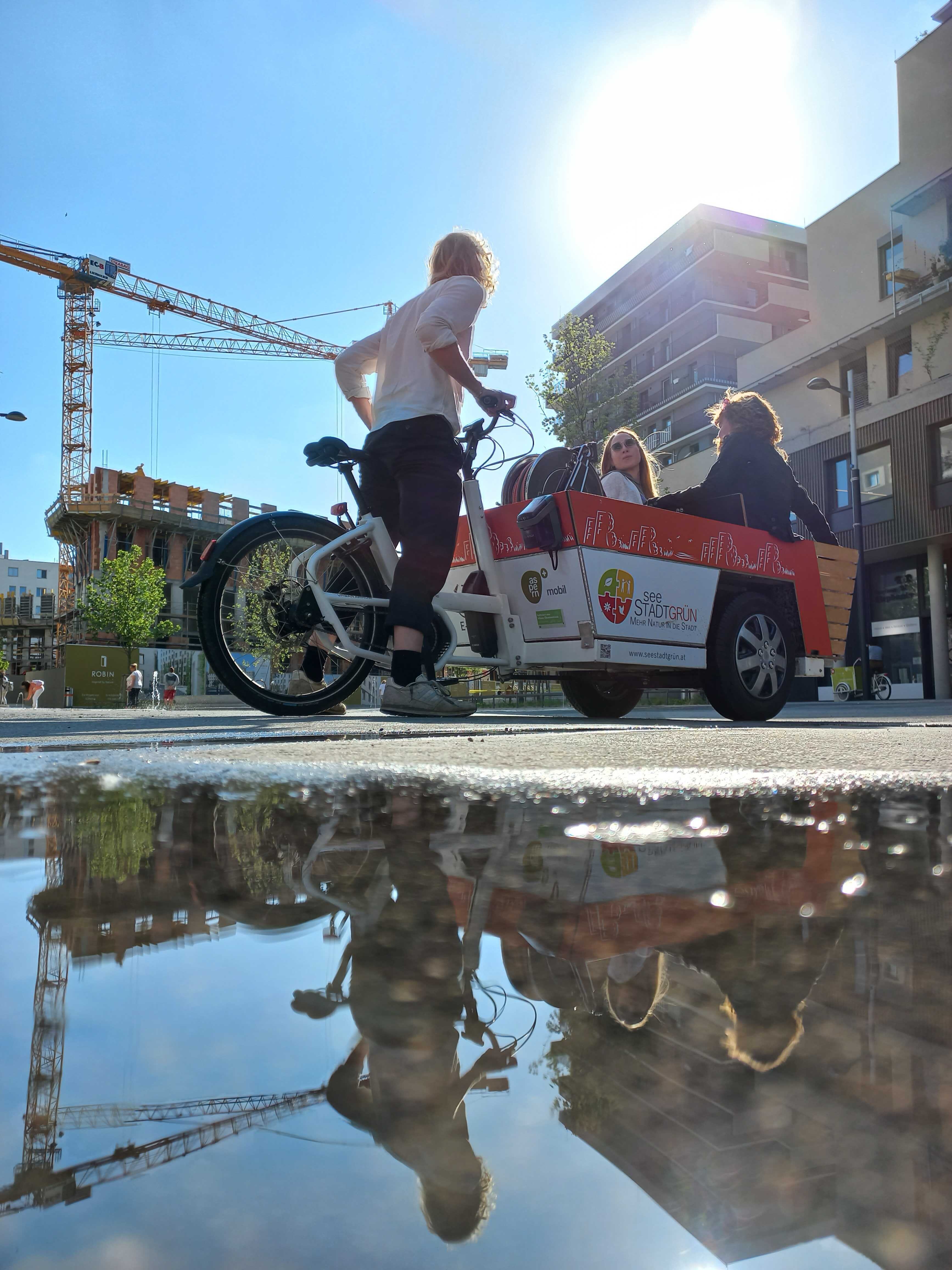 lastenfahrrad mit Menschen spiegelt sich im Wasser