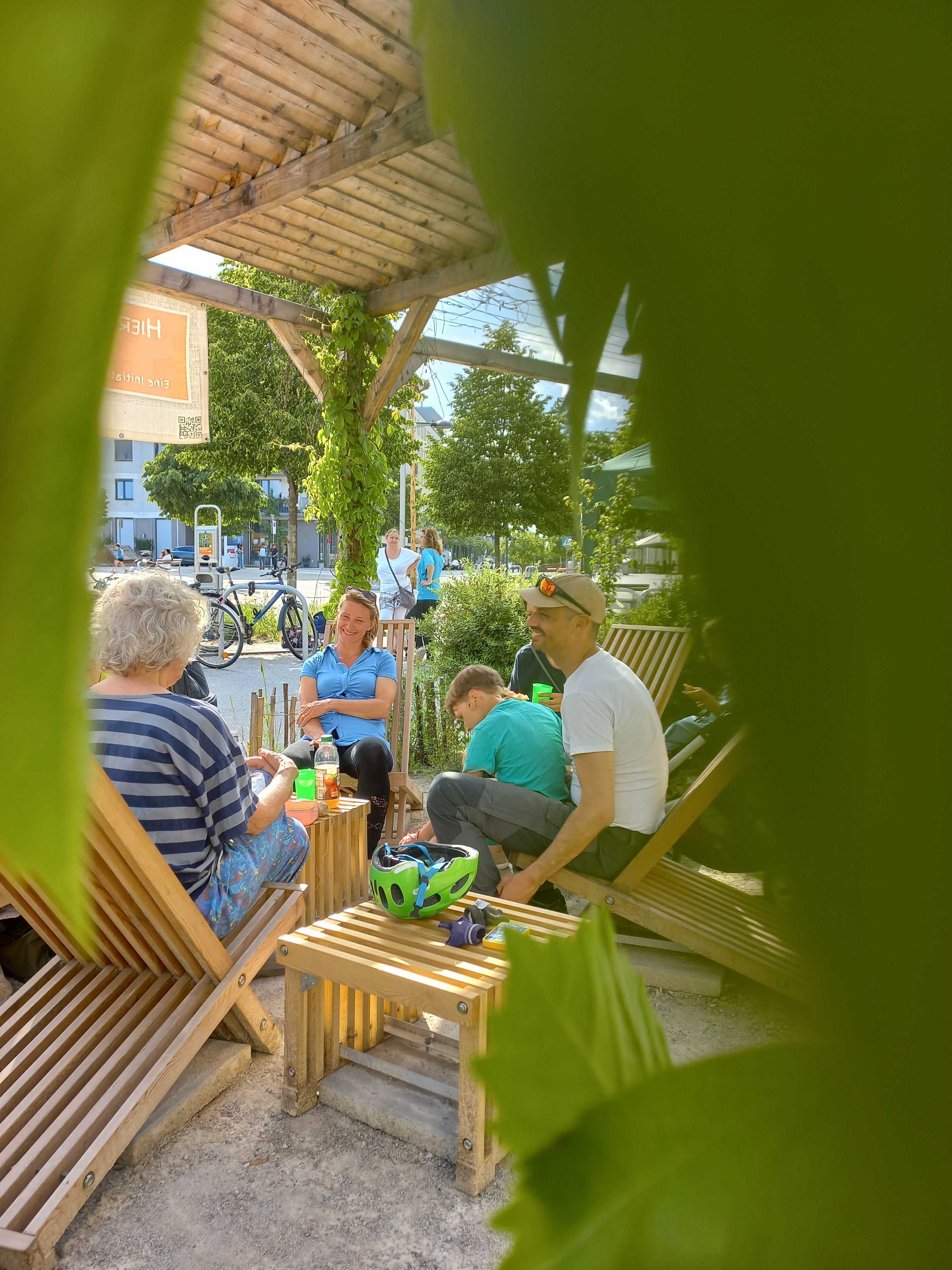 Menschen sitzen zusammen unter der Pergolar