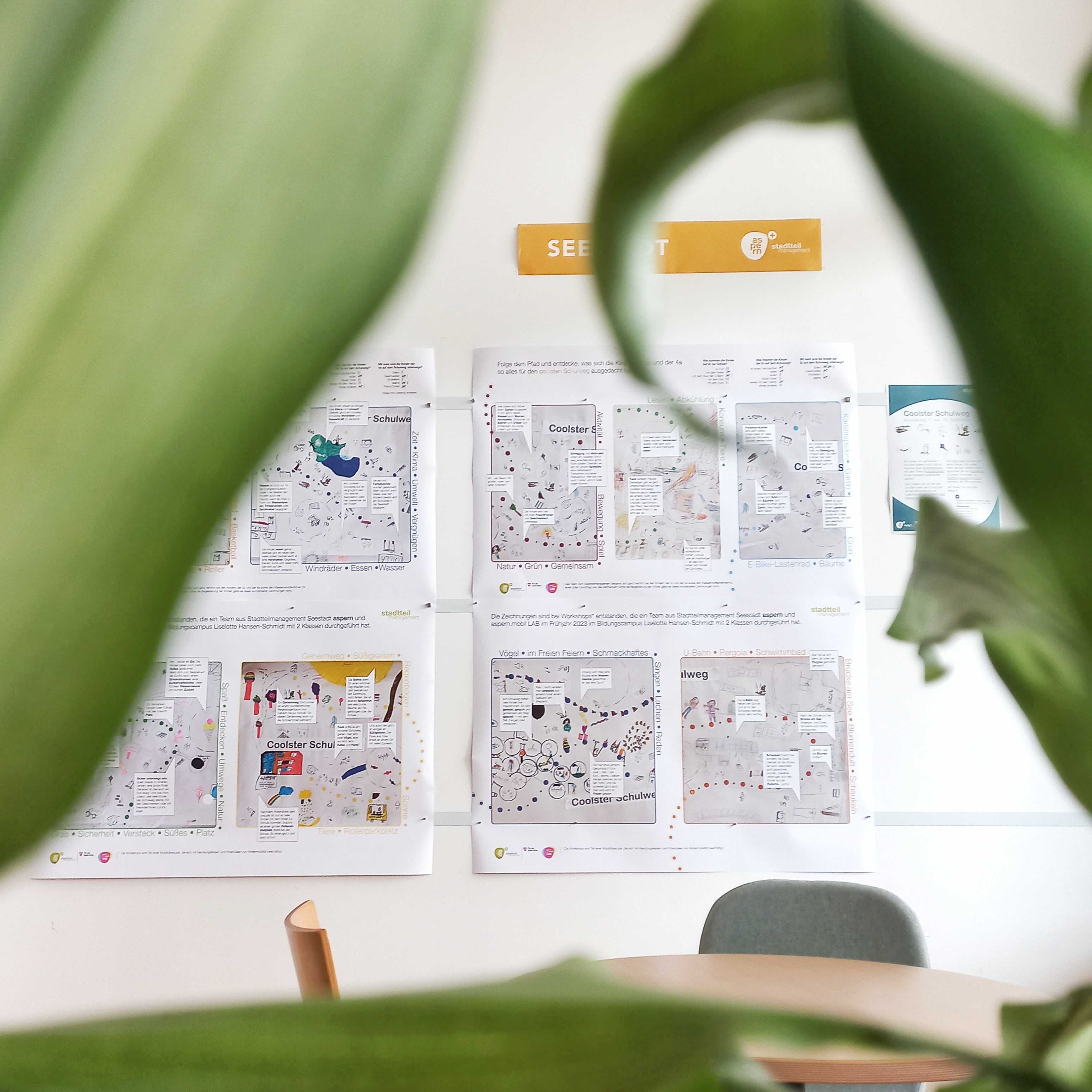 Im Vordergrund sieht man Pflanzen im Hintergrund die Plakate der Ausstellung für den Coolsten Schulweg