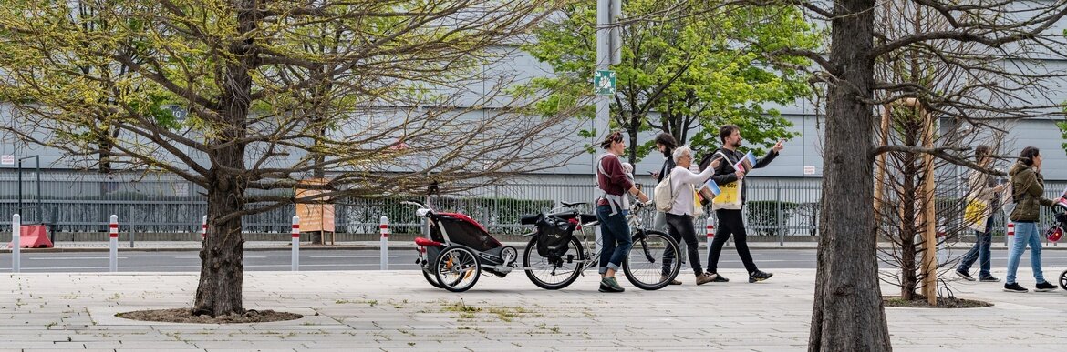 Menschen die zwischen Bäumen in der Stadt vorbei gehen
