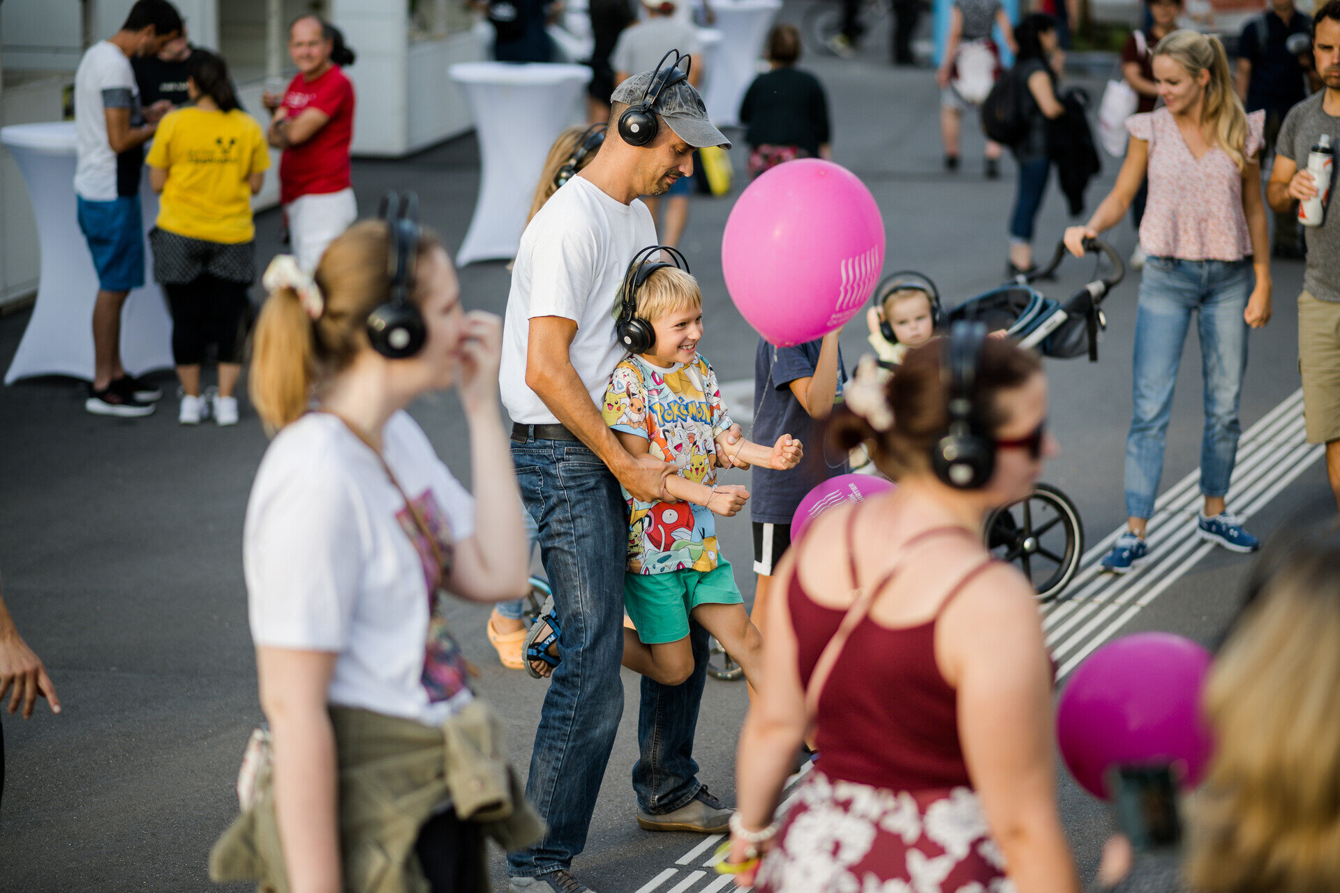 ein Kind hält einen Ballon in der Hand und wird von einem Mann hochgehoben