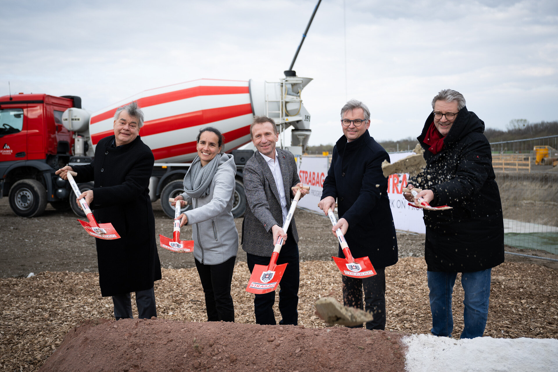 Vier Männer, eine Frau mit Spaten.