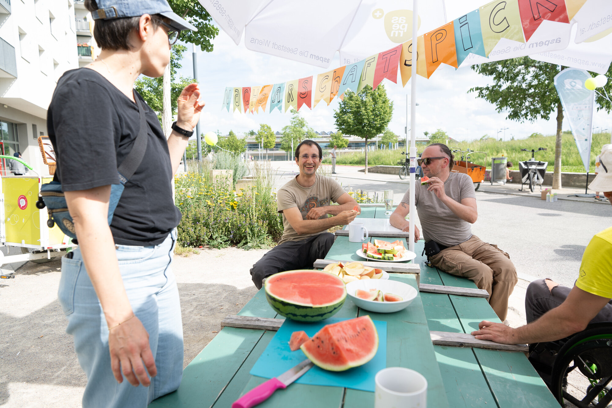 Menschen sitzen an einem Tisch und essen Wassermelone