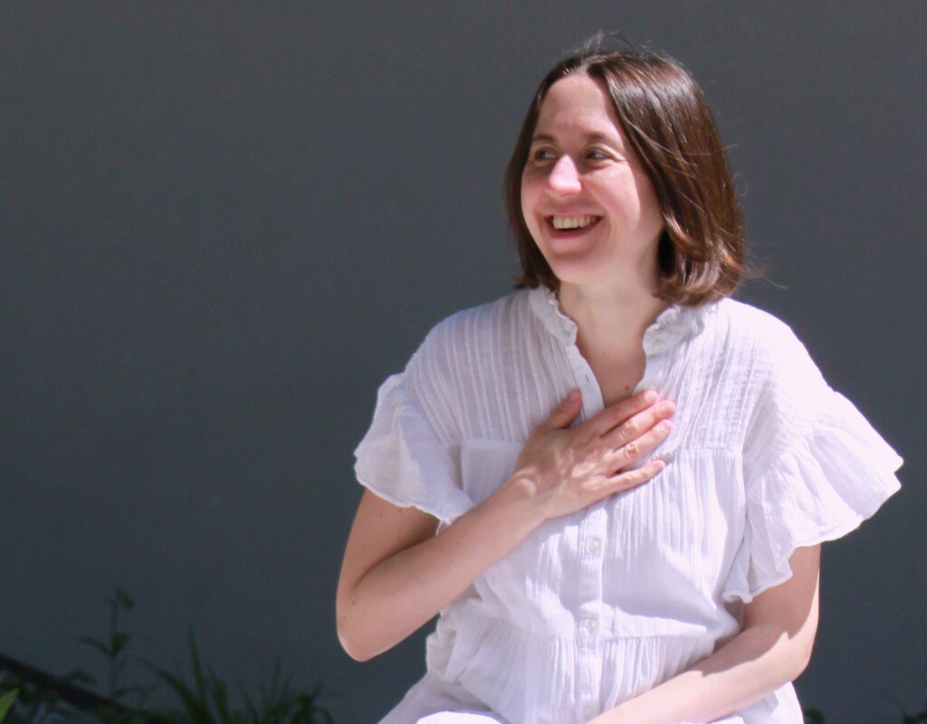 ein Frau die sich mit ihrer Hand aufs Herz greift.