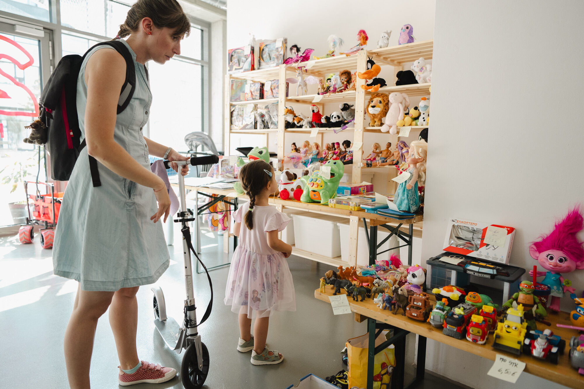 Kind und Frau stehen vor einem Tisch voller Spielsachen