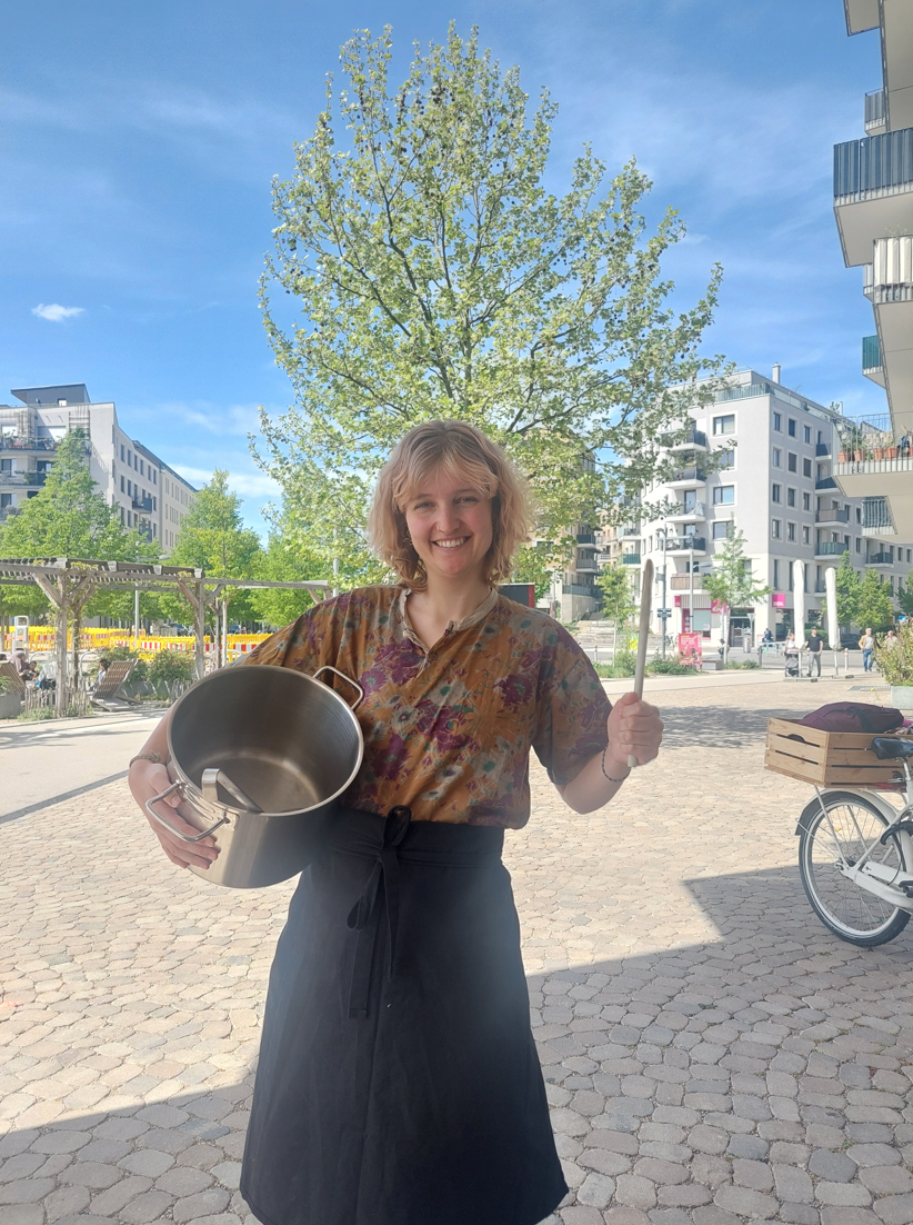 Mensch mit Kochschürze und Topf in der Hand