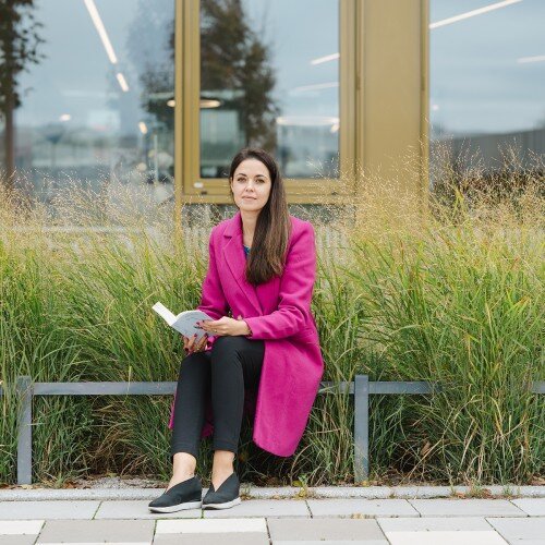 Anastasiya Blach sitzend auf einer Bank mit Buch in der Hand.