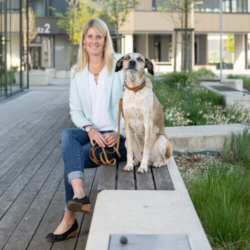 Nicole Bruny Nicole Bruny sitzend auf einer Bank. Vor ihr sitzt ein Hund.