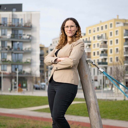 Elisabeth Dunkel stehen auf einer Wiese. Hinter ihr befinden sich hohe Gebäude.