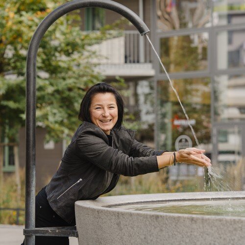 Colette Grillowitzer stehend an einem Brunnen.