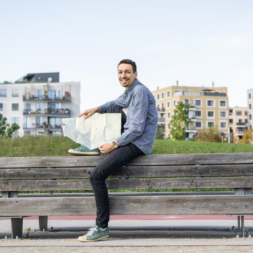 Morten Konturek sitzend auf einer Bank mit einer Stadtkarte in der Hand.