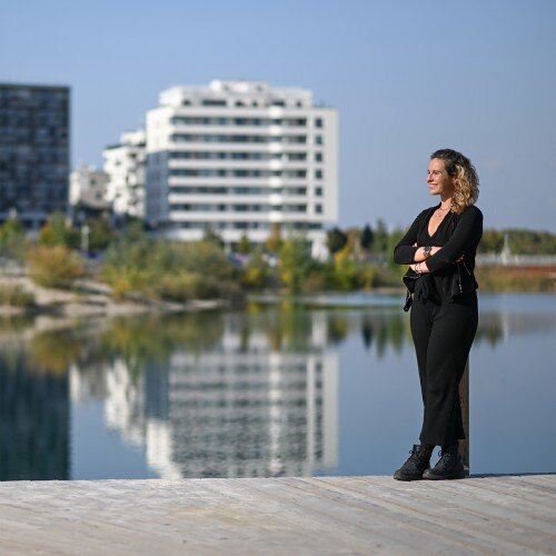 Nikola Frizberg-Nilsson stehend an einem See. Sie blickt in die Ferne und lächelt dabei.