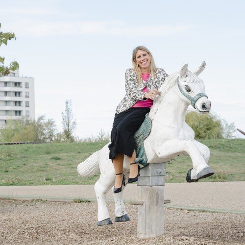 Barbara Poisl sitzt auf einem Spielzeugpferd.