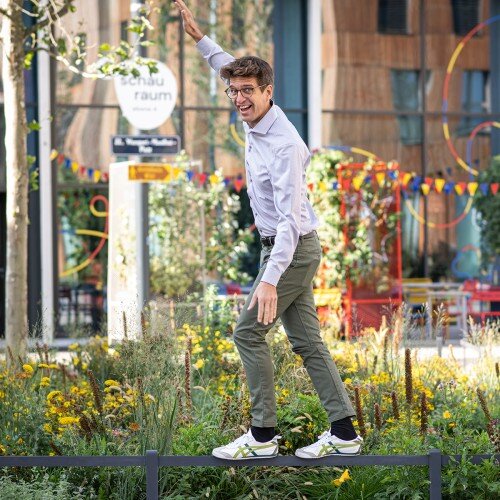 August Rollwagen balancierend auf einem Geländer. Hinter ihm einen Blumenwiese.